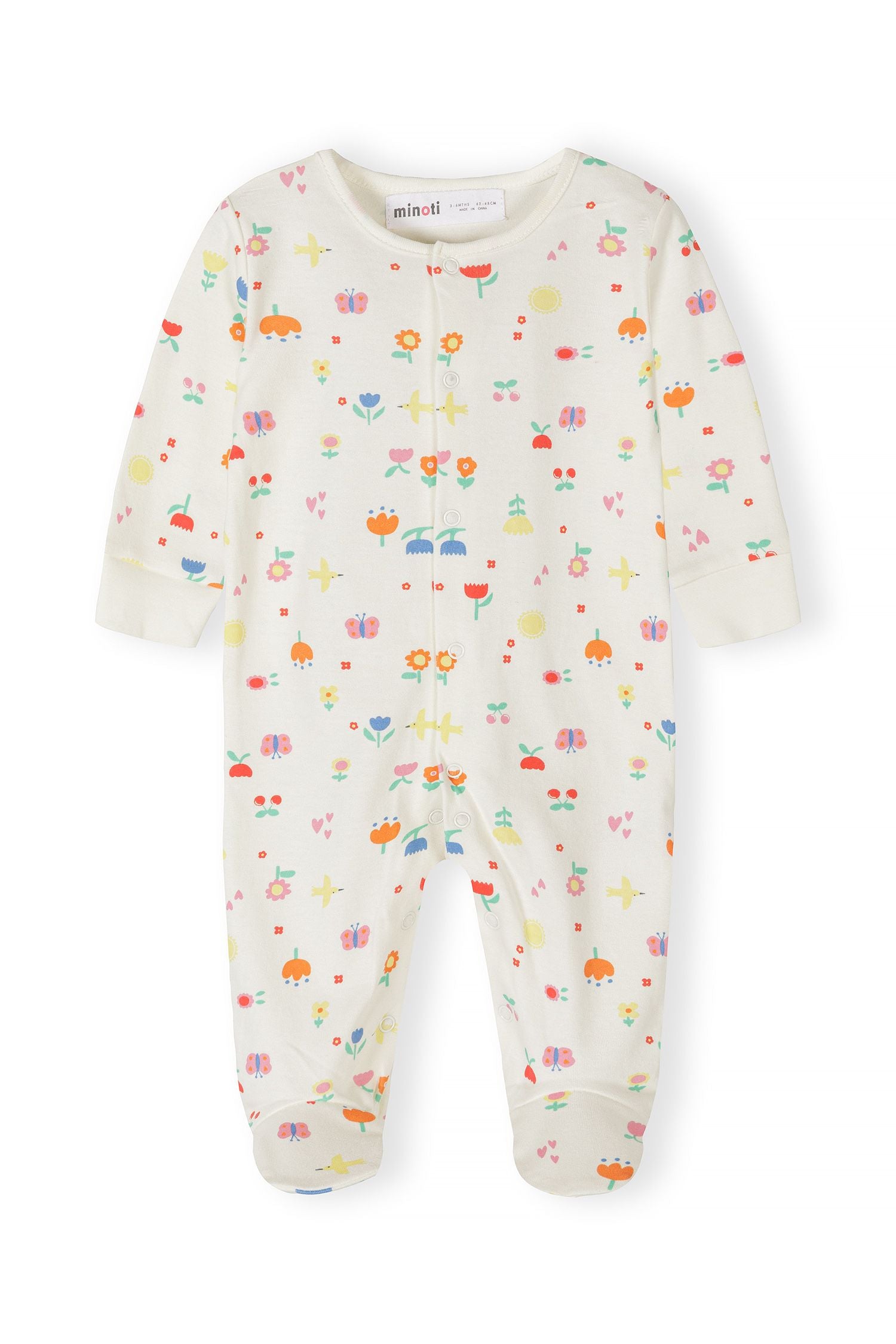 Detail of a girls' cotton sleepsuit with floral and polka dot patterns, featuring long sleeves and press studs.