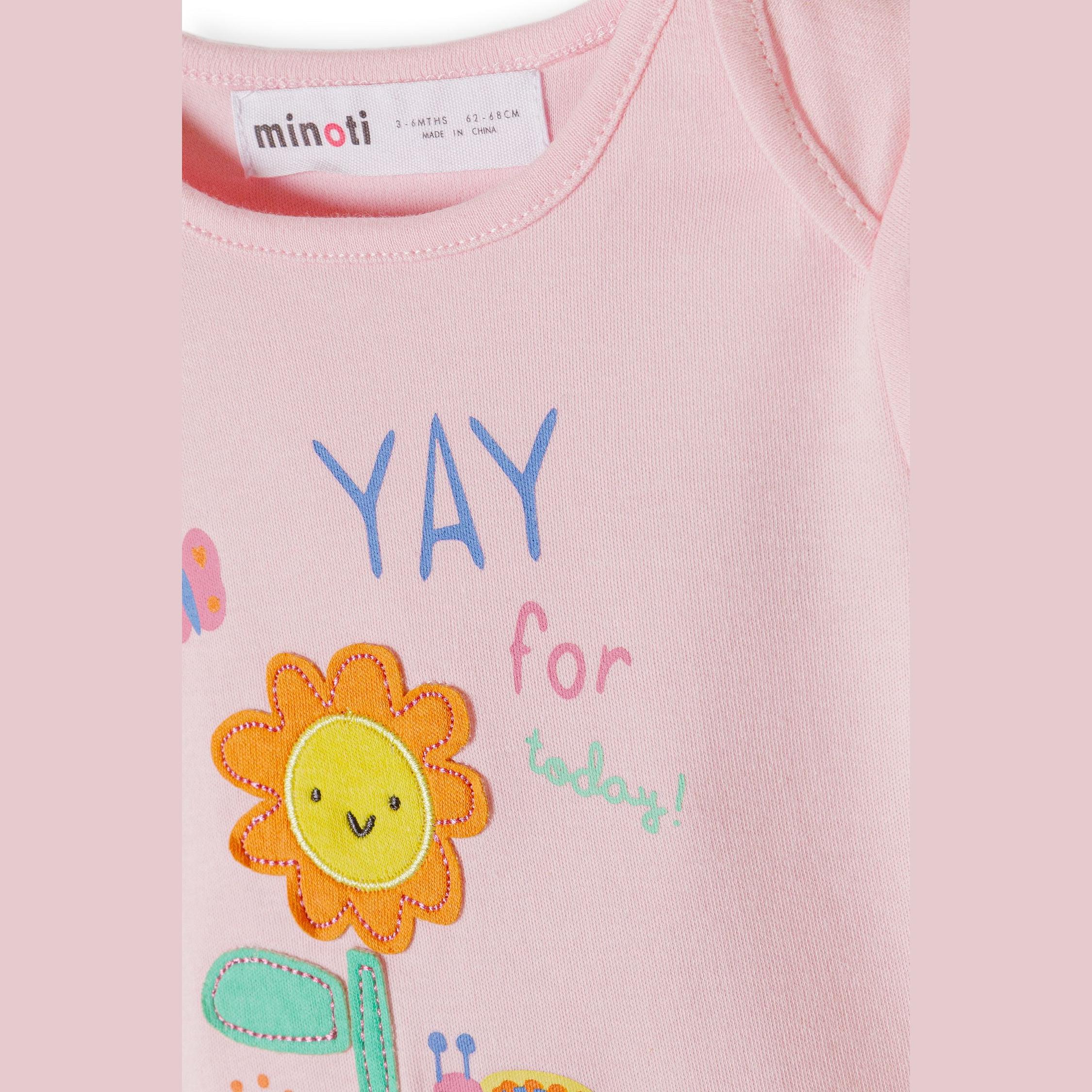 Close-up detail of pink bodysuit showing YAY for today text with appliqué sunflower design and Minoti label at neckline