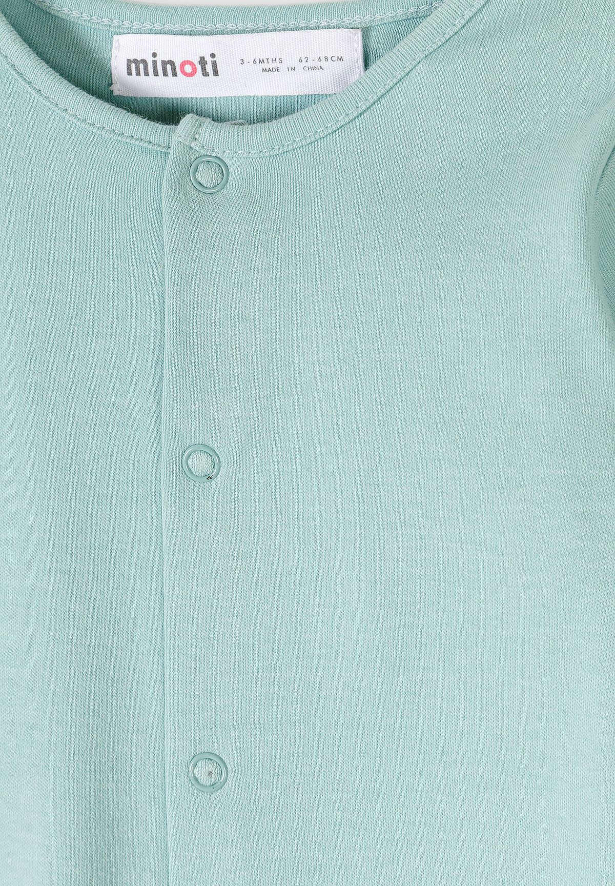 Close-up of the mint baby sleepsuit's round neckline and fabric-covered press studs along the front placket.