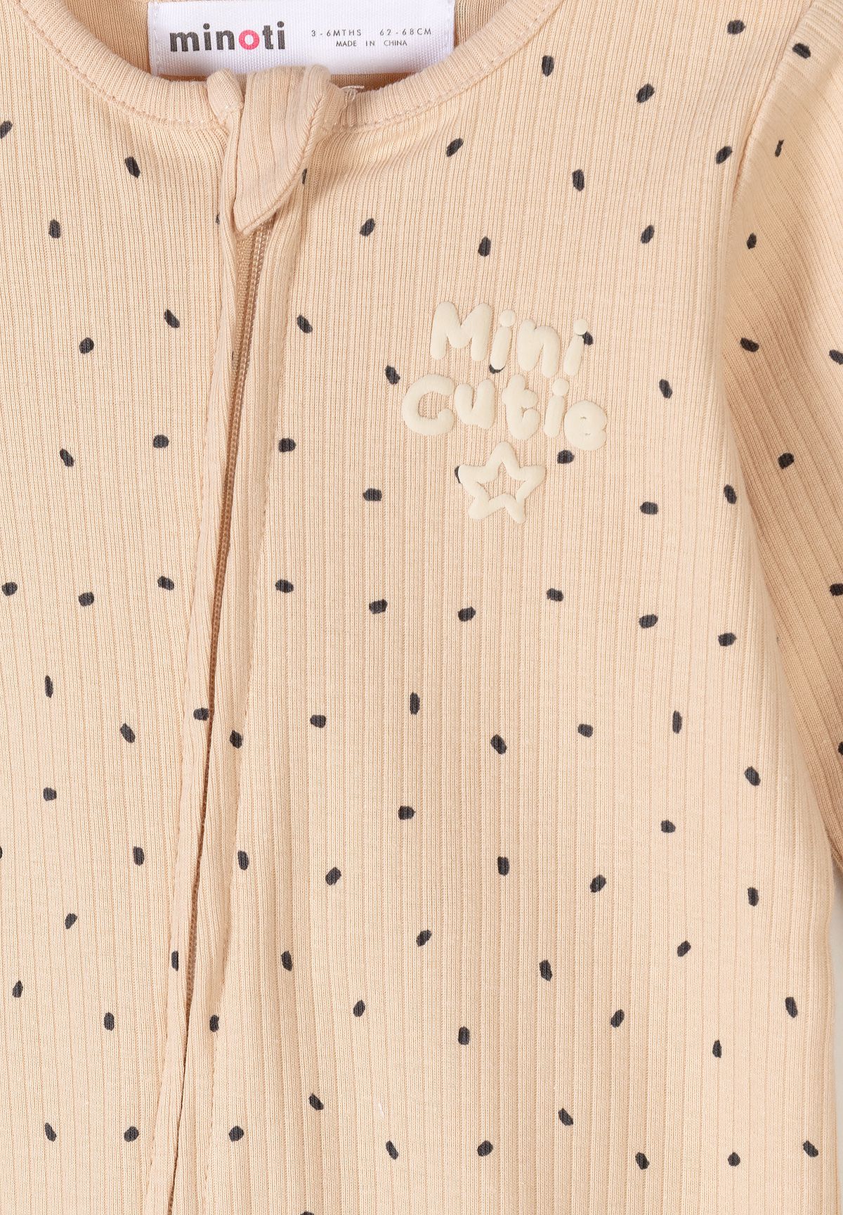 Beige sleepsuit close-up showing rib texture, Mini cutie print and zip guard.