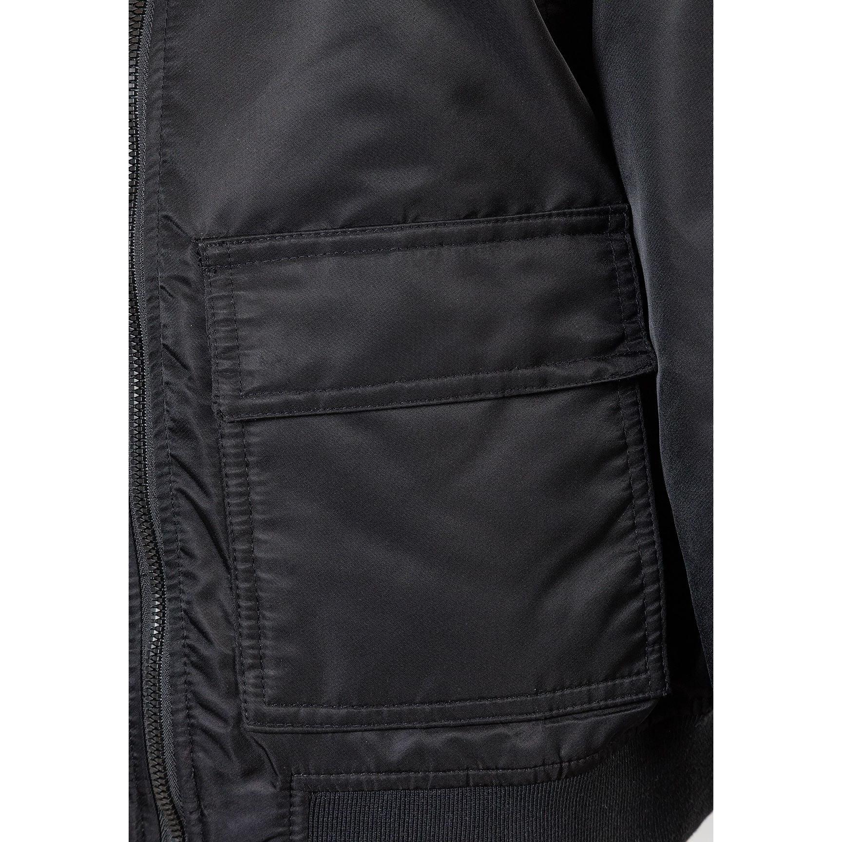 Interior view of black bomber jacket showing multiple utility pockets and lining detail