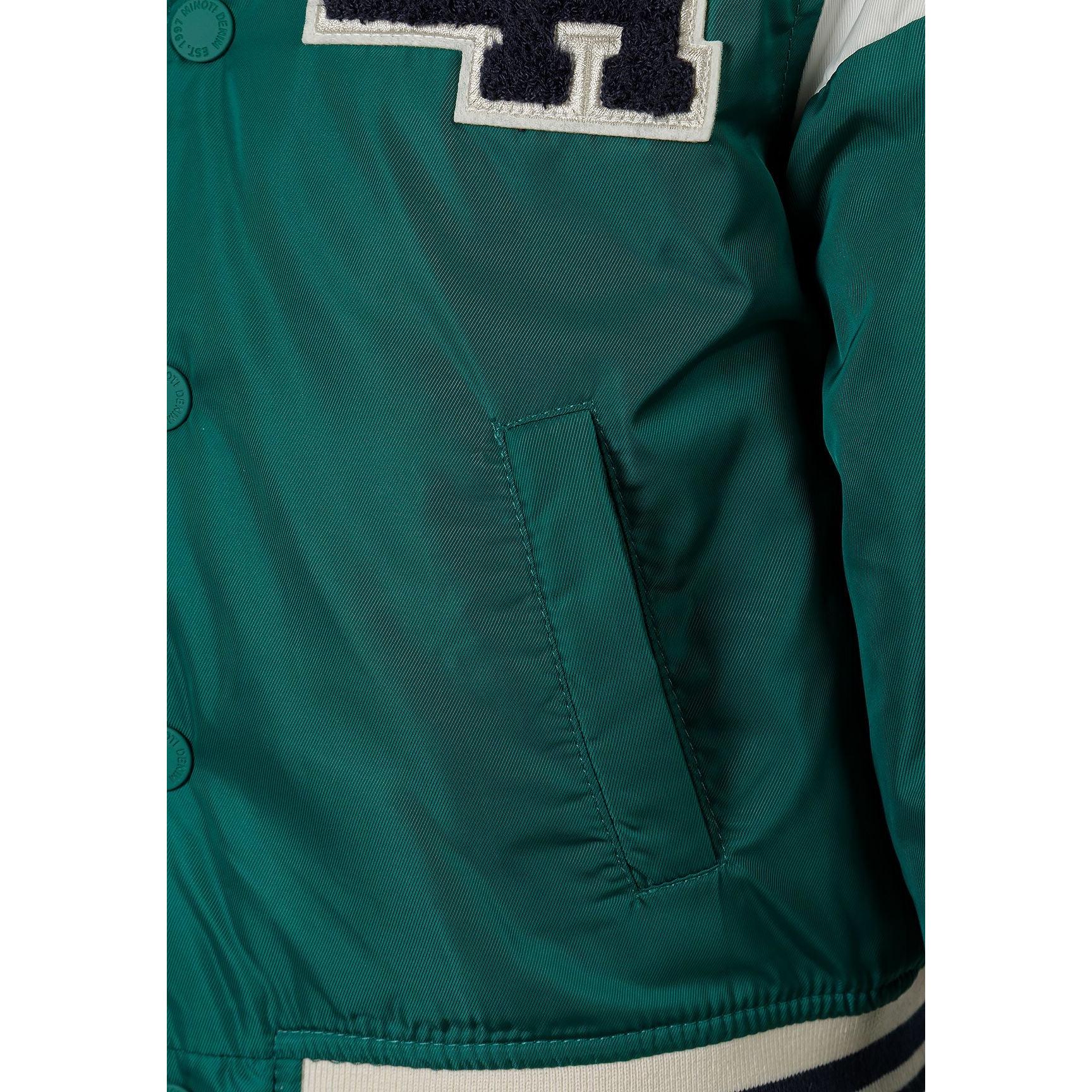 Close-up detail of green bomber jacket showing side pocket and partial LA patch with navy and cream lettering