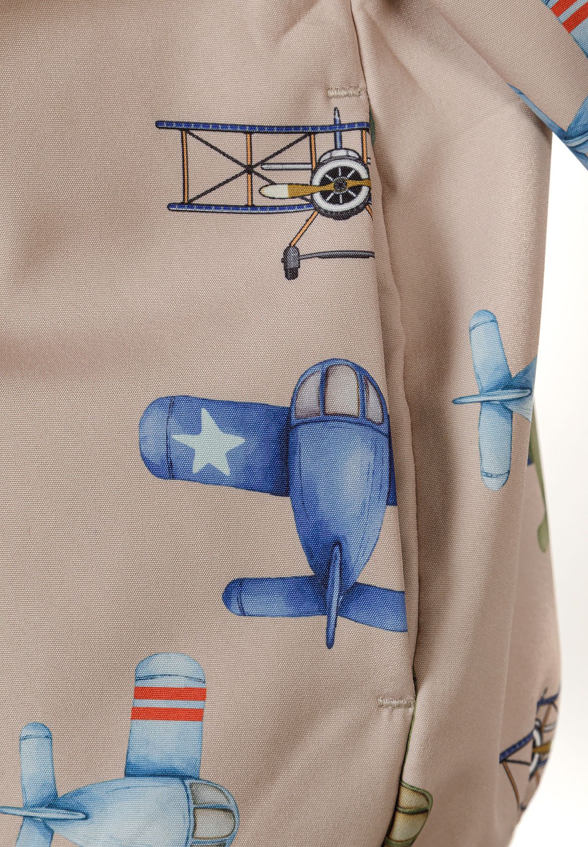 Close-up of beige jacket side pocket beside blue propeller planes and biplanes.