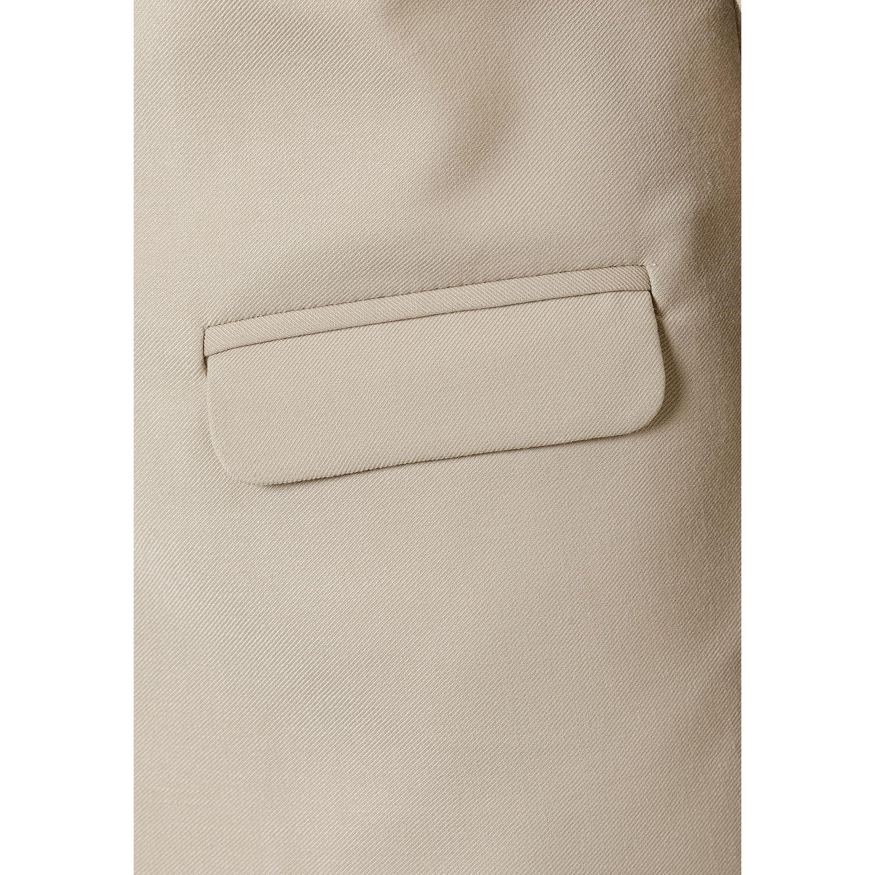 Close-up detail of stone blazer chest pocket showing tailored construction and fabric texture