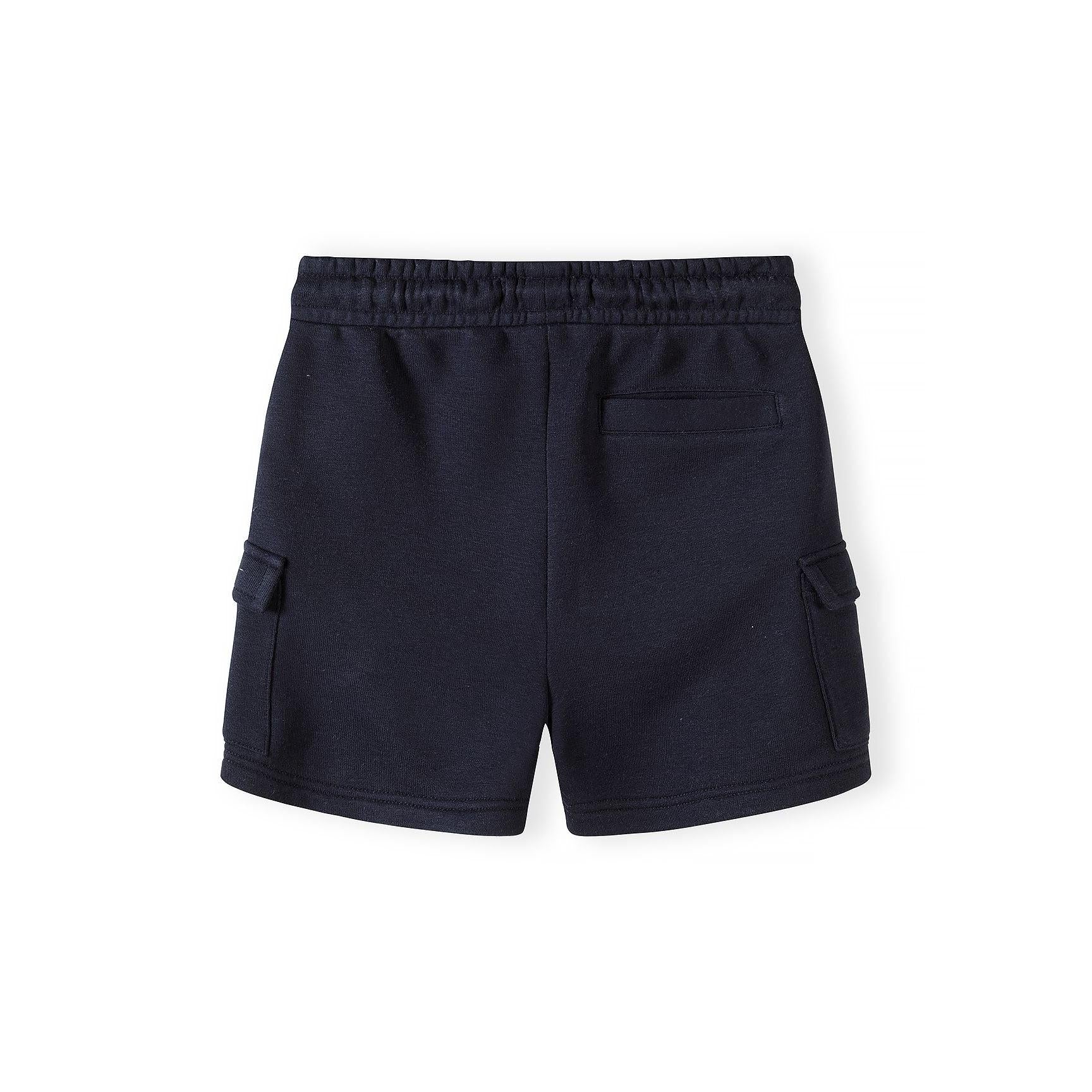 Detail shot of navy cargo shorts waistband area showing Minoti brand label, elasticated waistband with drawstring and side cargo pocket construction