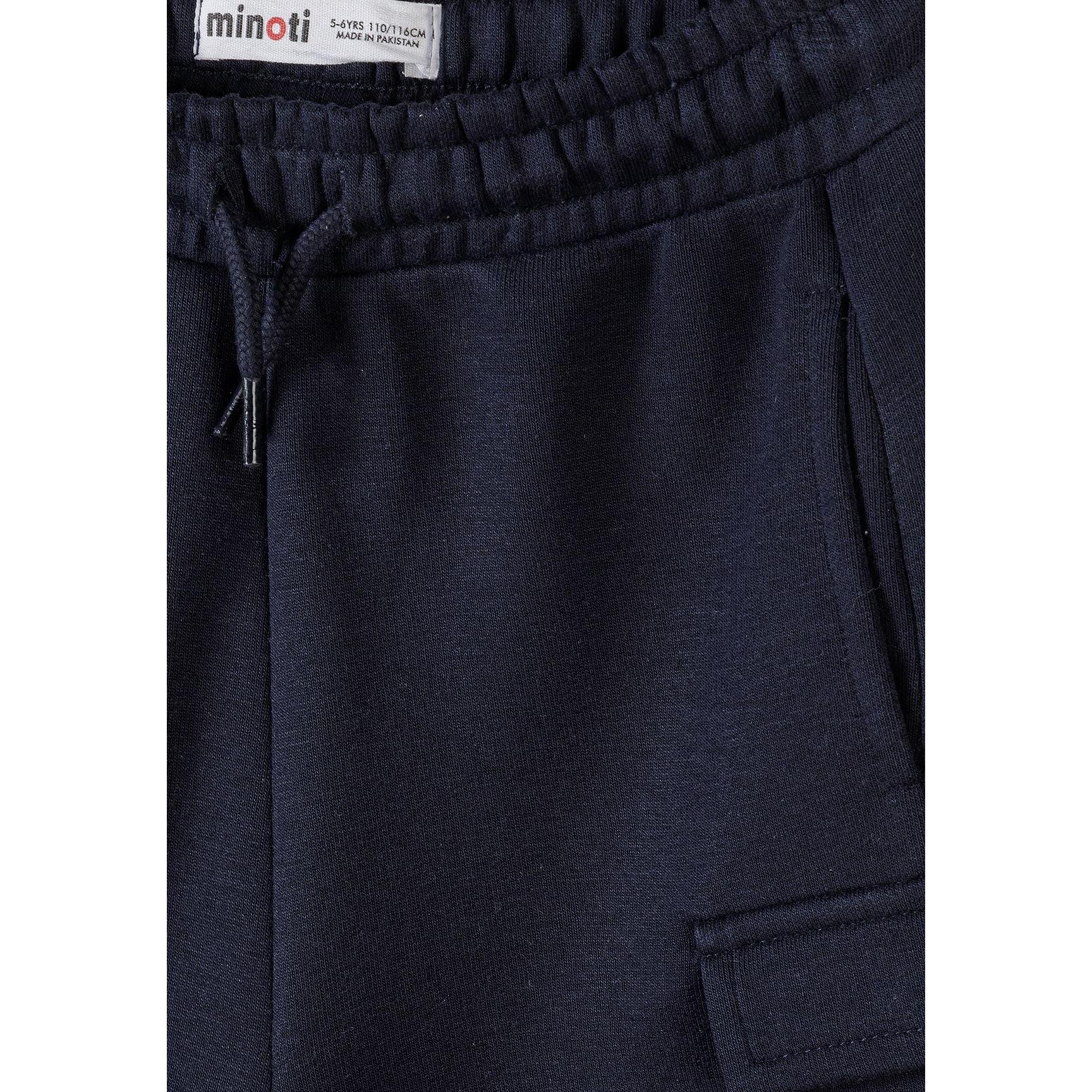 Detail shot of navy cargo shorts waistband area showing Minoti brand label, elasticated waistband with drawstring and side cargo pocket construction