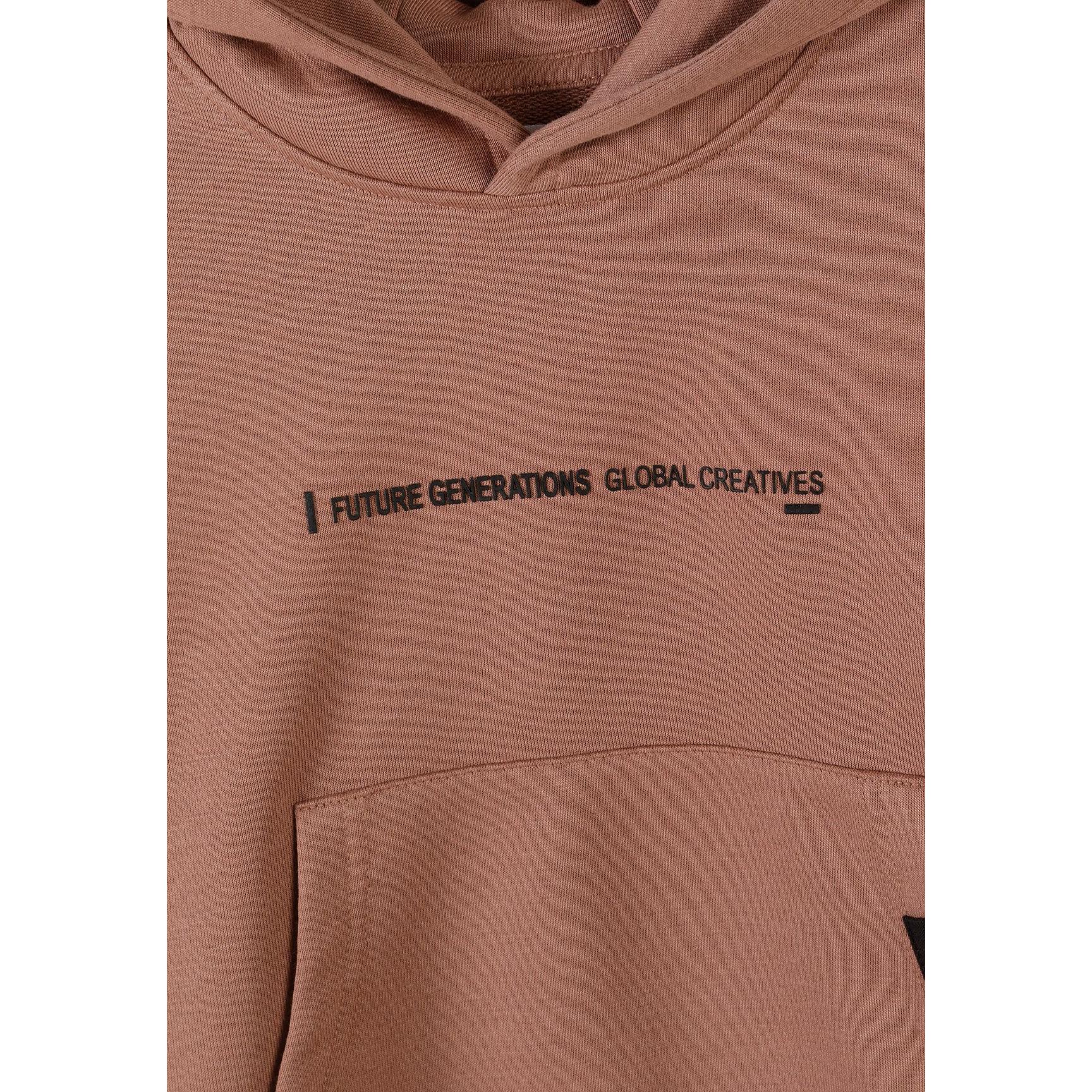 Close-up detail of cognac joggers showing drawstring waistband and vertical text print on thigh area