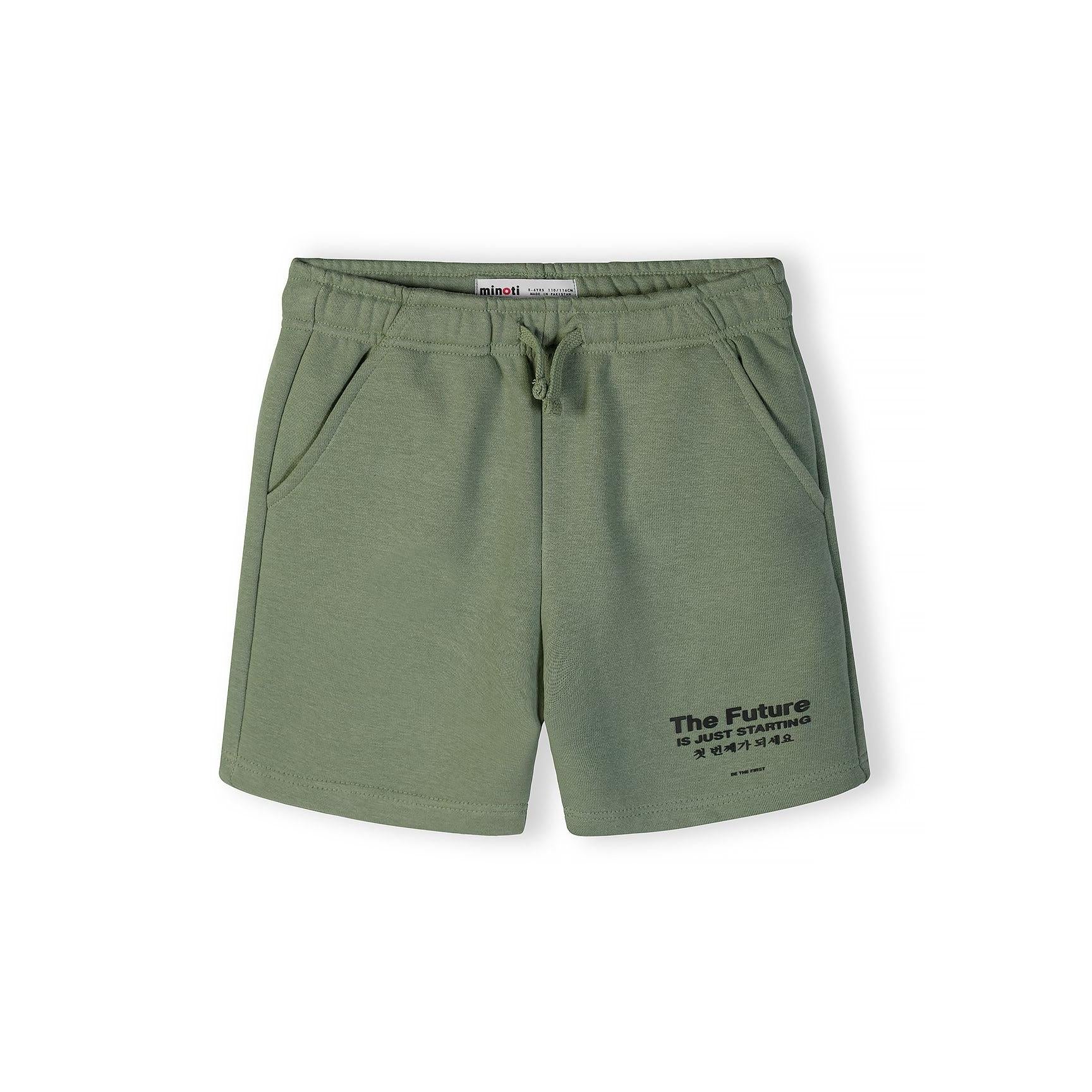 Flat lay of olive green shorts with drawstring waist and 'The Future Is Just Starting' print on leg, showing Minoti label on white background