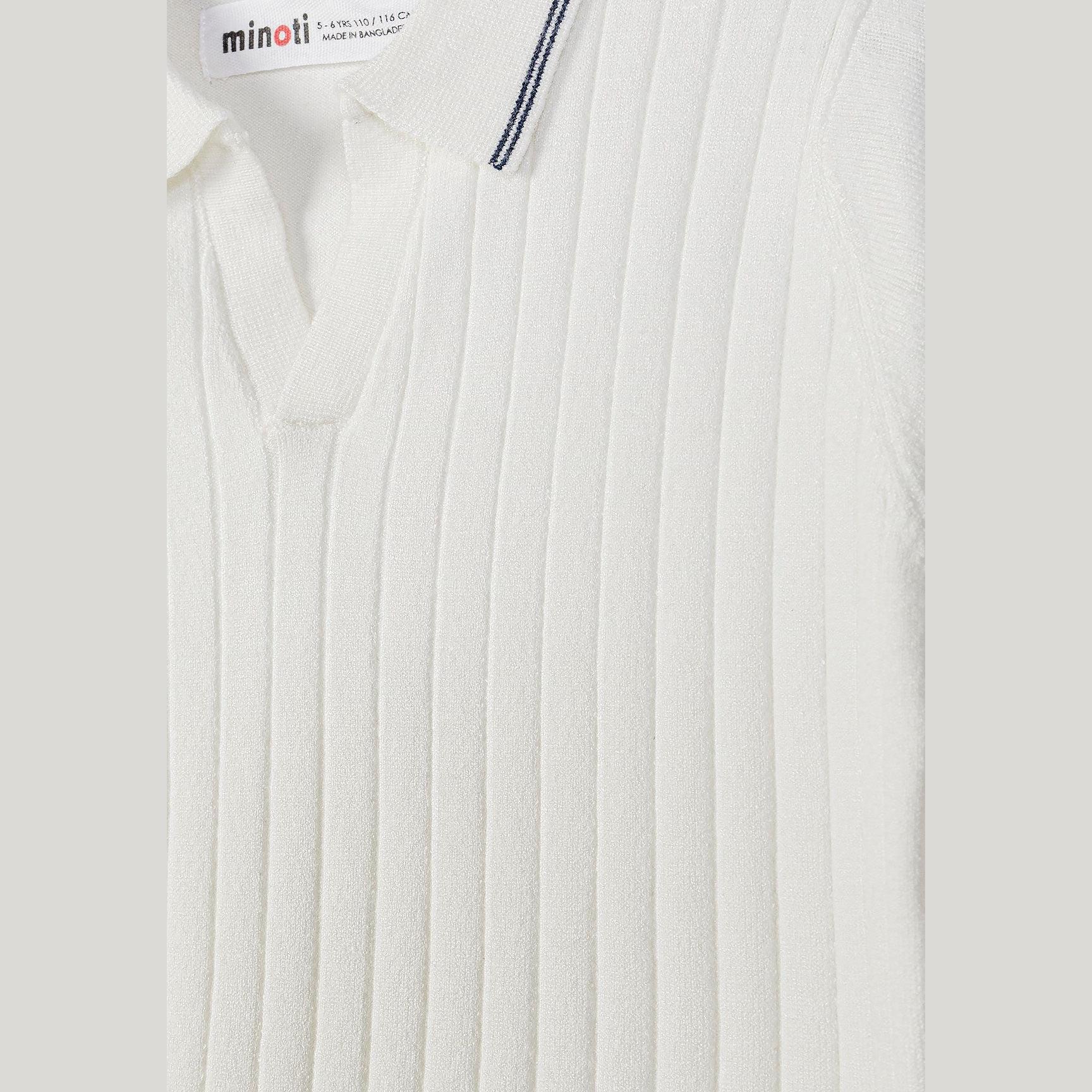 Close-up detail of Minoti label and vertical striped knit texture on off white polo shirt showing quality craftsmanship
