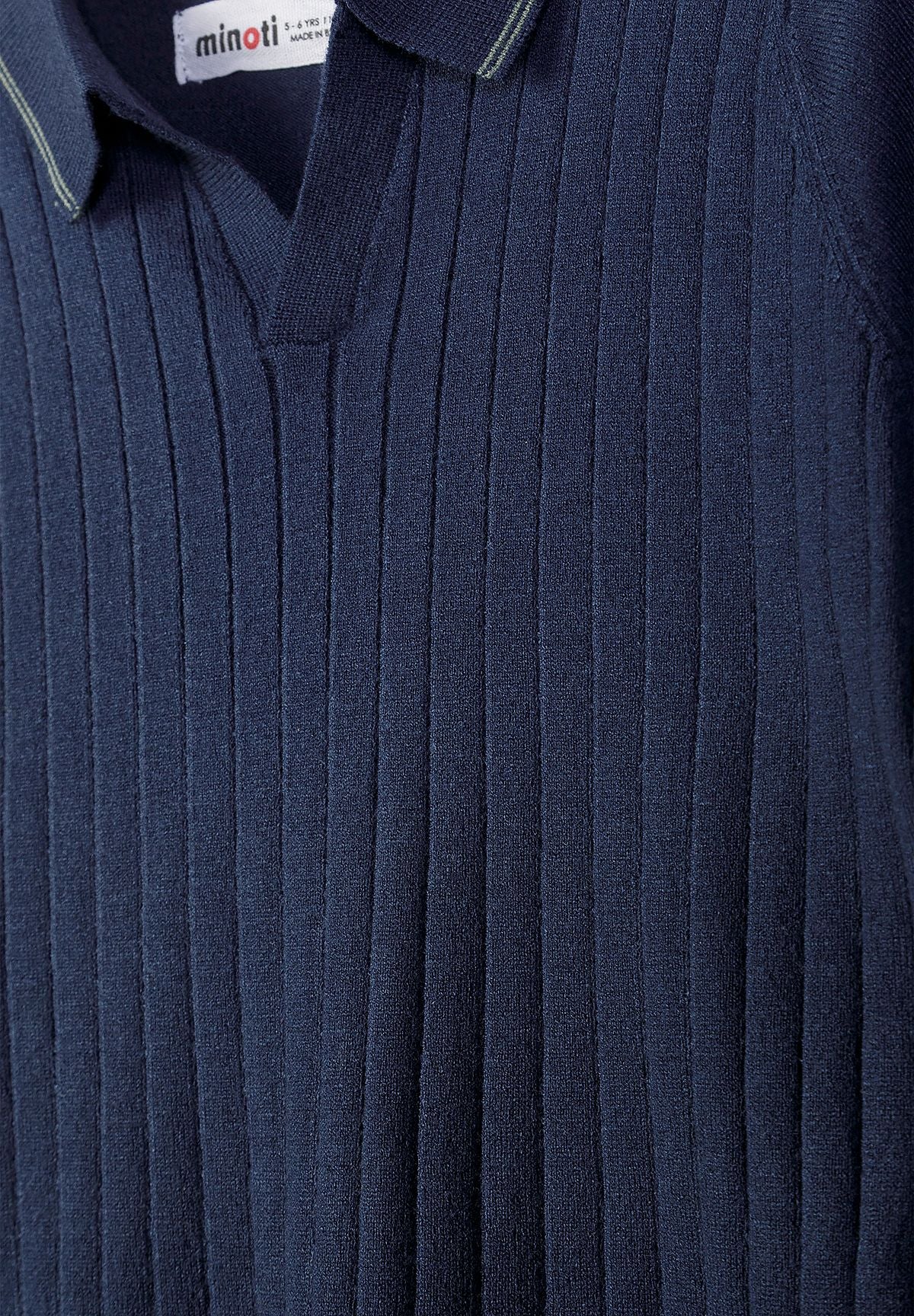Close-up of navy polo's buttonless V collar and vertical ribbed front.