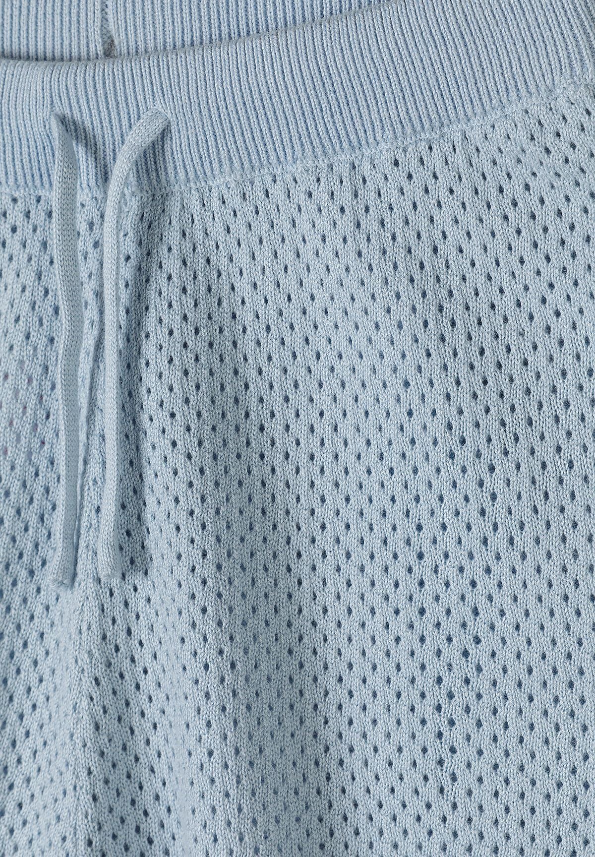 Detail of light blue elastic shorts with a textured knit and drawstring.