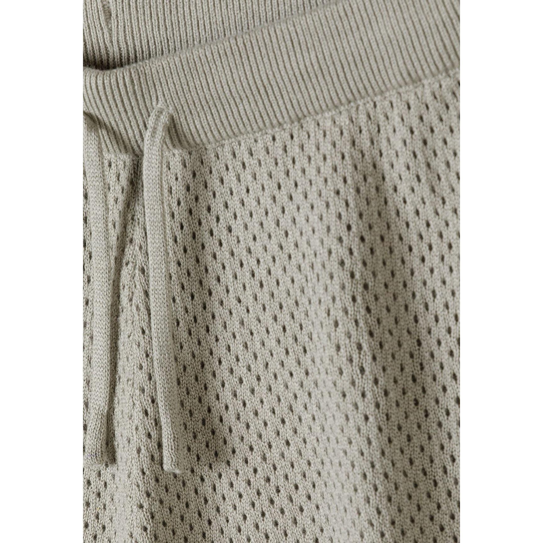 Close-up detail of khaki knitted shorts waistband showing textured mesh pattern fabric and drawstring tie on white background