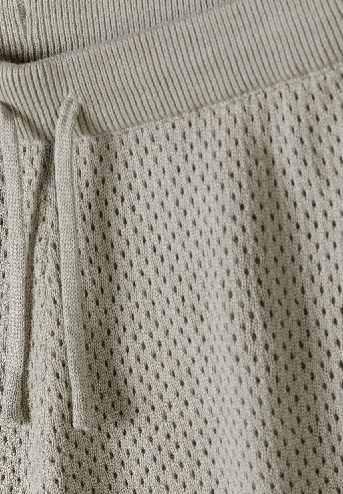 Close-up of grey-green shorts ribbed drawcord waist and openwork knit.