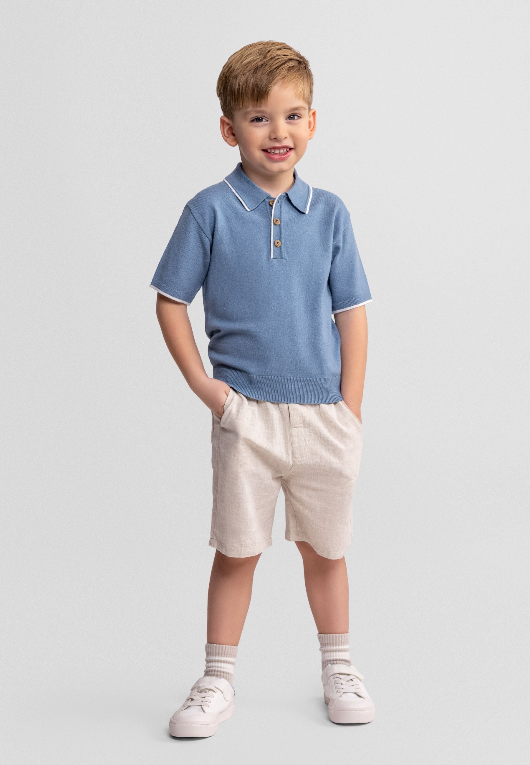 Boys light blue polo shirt with beige shorts, front view, featuring buttons and side pockets.
