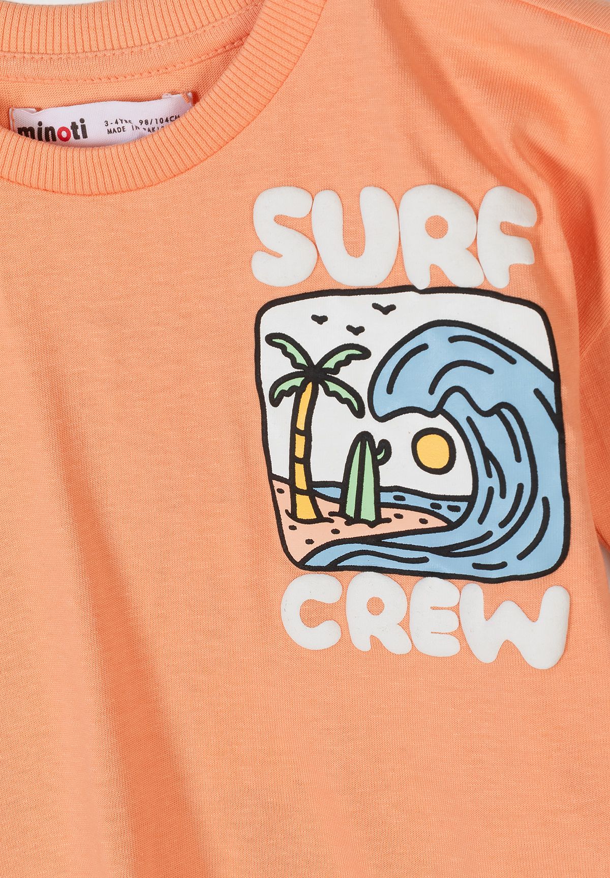 Close-up of apricot boys' t-shirt featuring a surf graphic and ribbed crew neckline.