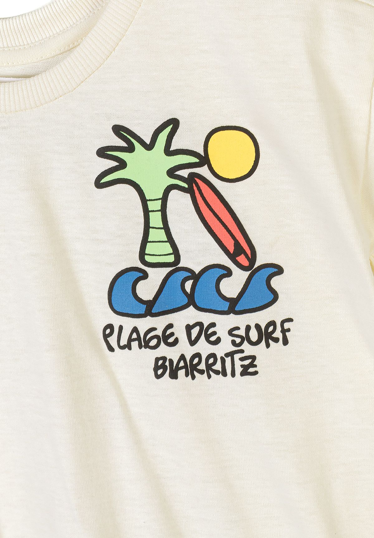 Detail of a beige t-shirt featuring a colorful surf-themed graphic.