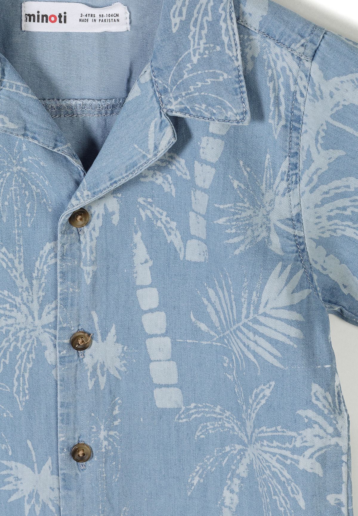 Detail of a boys' short sleeve denim shirt with palm leaf print and button-down front.