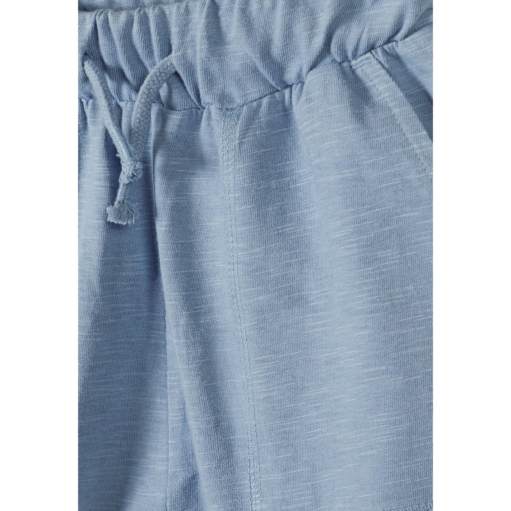 Close-up detail of light blue cotton jersey shorts showing drawstring waist with cord ties and fabric texture