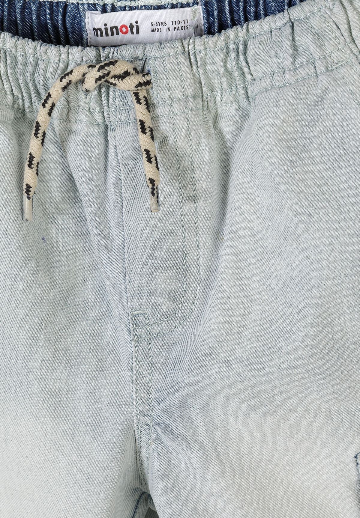 Close-up detail of light blue denim cargo shorts showing Minoti label, elastic waistband with rope drawstring and cargo pocket construction