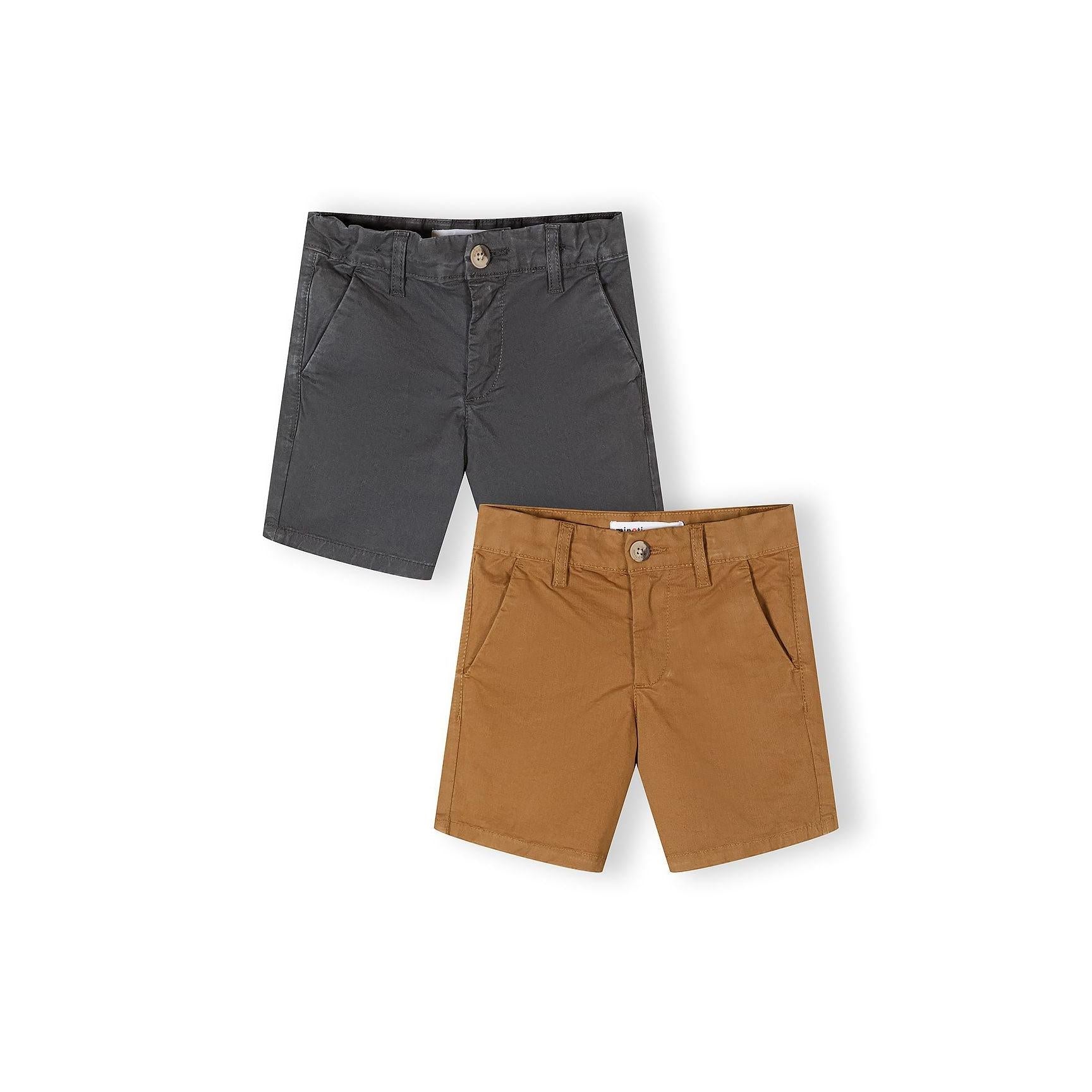 Two pairs of chino shorts displayed flat on white background - one in dark charcoal grey and one in warm sand brown color, both featuring classic tailored styling with button closure