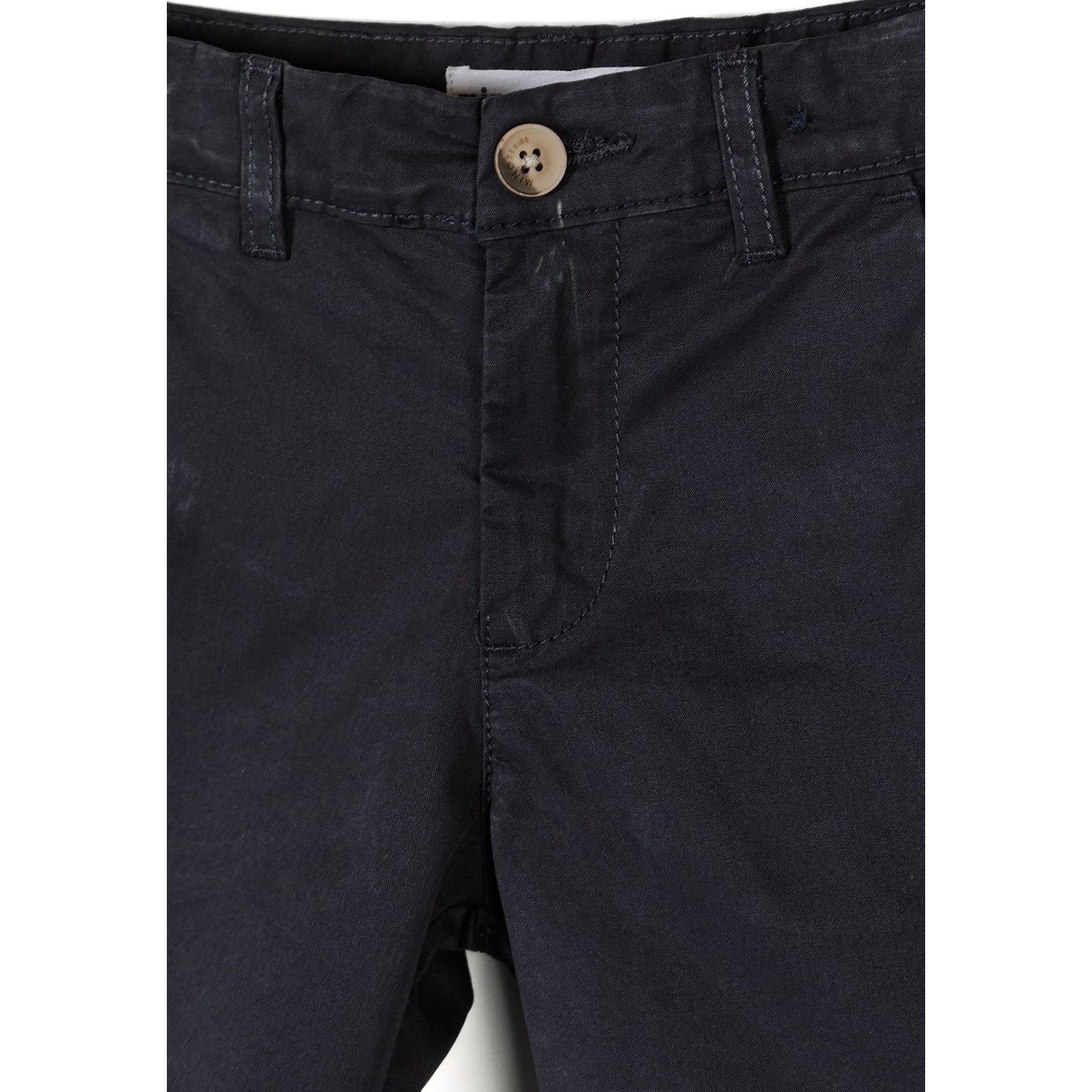 Close-up detail of navy chino shorts waistband showing button closure with natural wood-tone button and belt loops