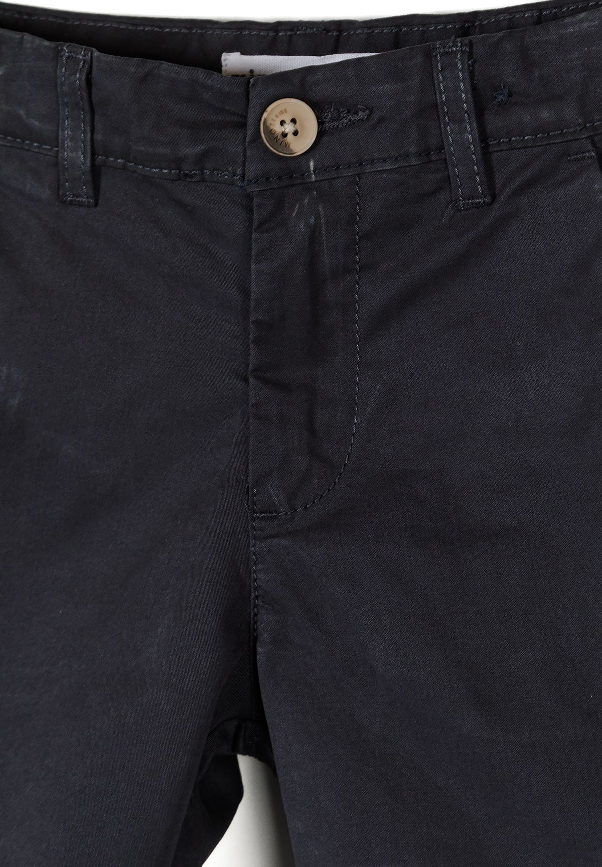 Close-up of the dark navy chino shorts' tan four-hole waist button, belt loops and stitched fly placket.