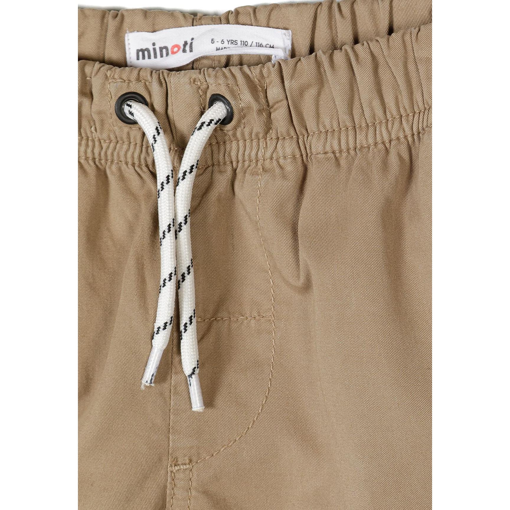 Close-up detail of sand beige shorts showing Minoti label, white drawstring with black stripe detail and front pocket stitching