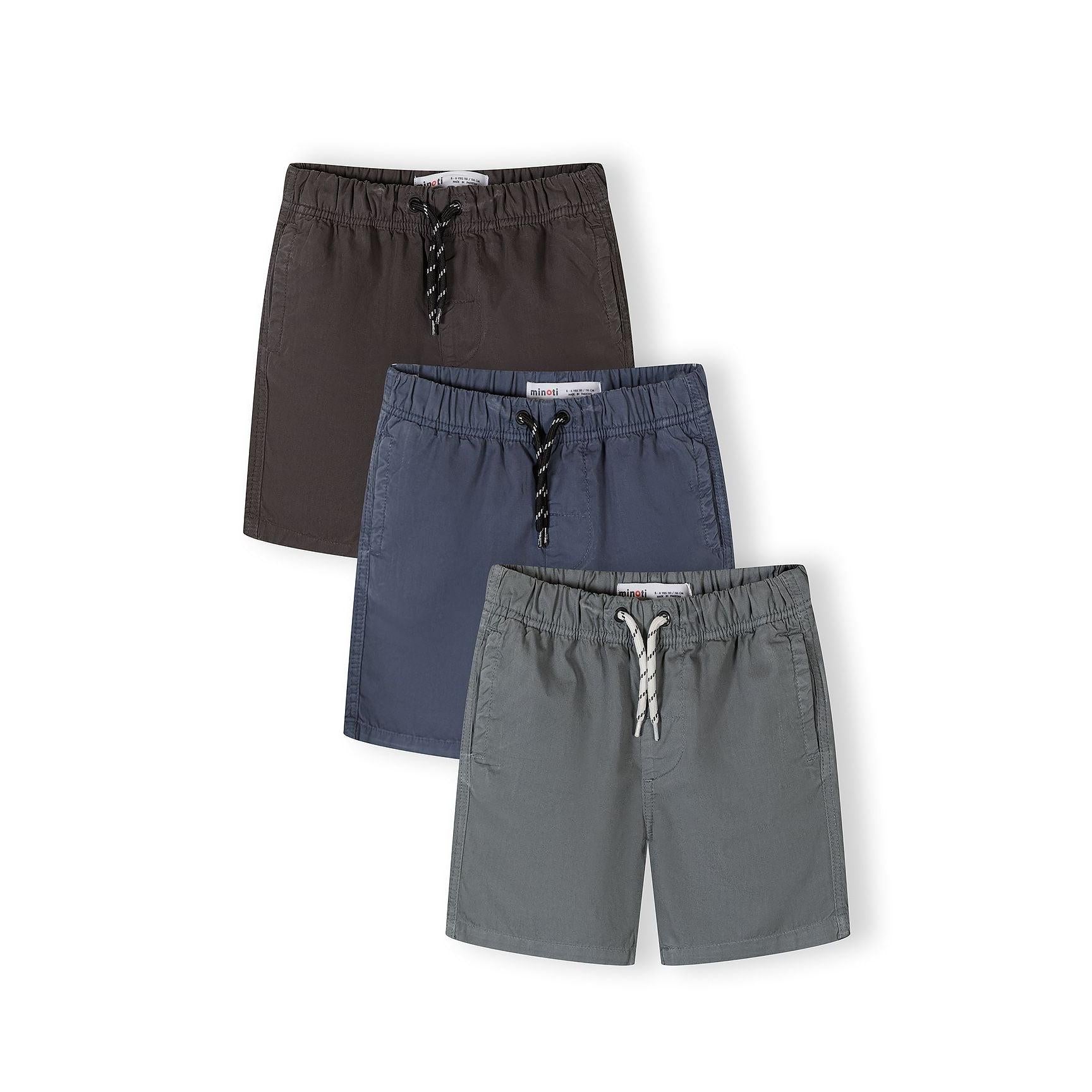 Three woven cotton shorts in grey, blue and navy laid flat showing elasticated waistbands with drawstring ties on white background