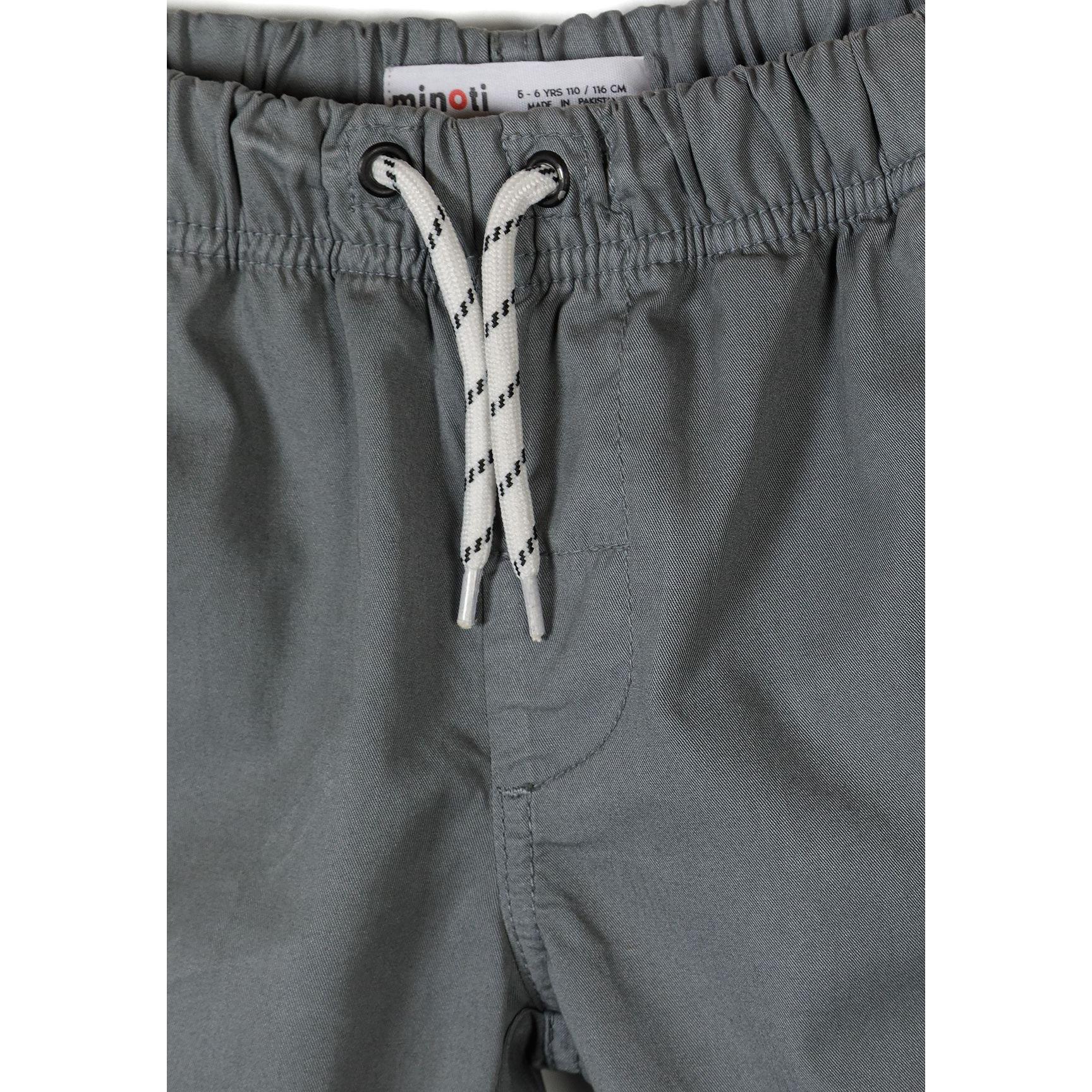 Close-up detail of grey shorts waistband showing Minoti label, elasticated gathering and white drawstring with black pattern detail