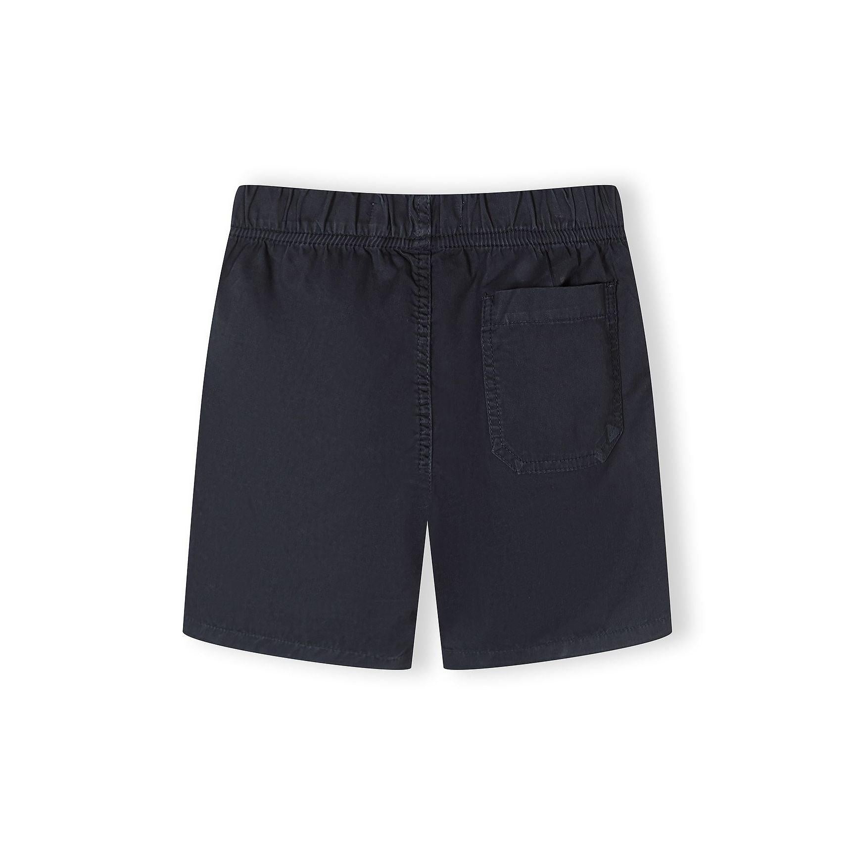 Detail shot of navy shorts waistband showing Minoti brand label and white drawstring with navy pattern against fabric texture