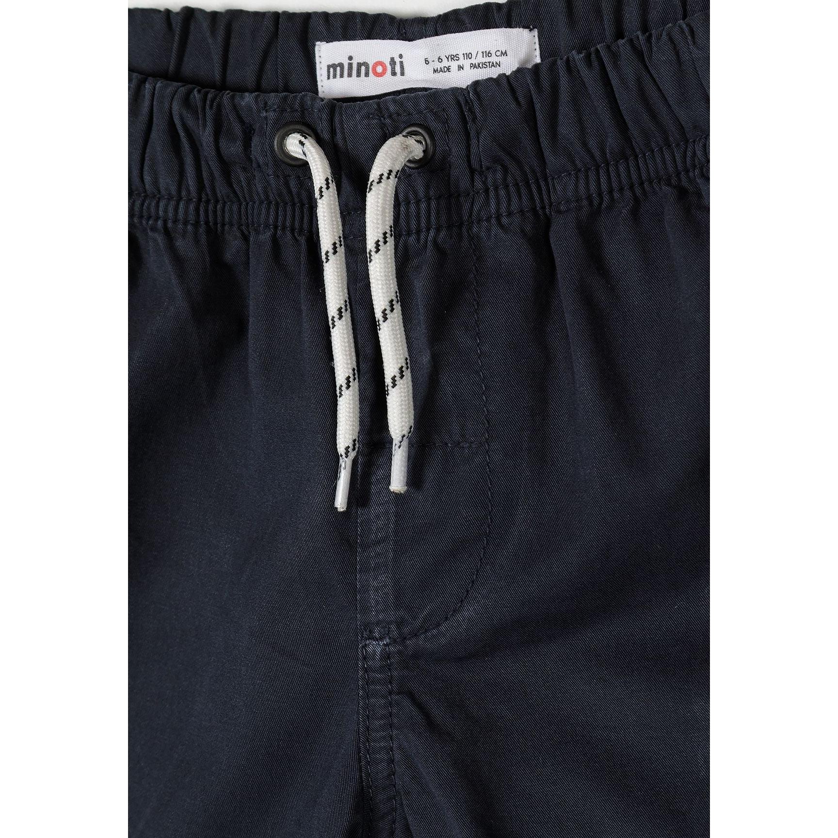 Detail shot of navy shorts waistband showing Minoti brand label and white drawstring with navy pattern against fabric texture