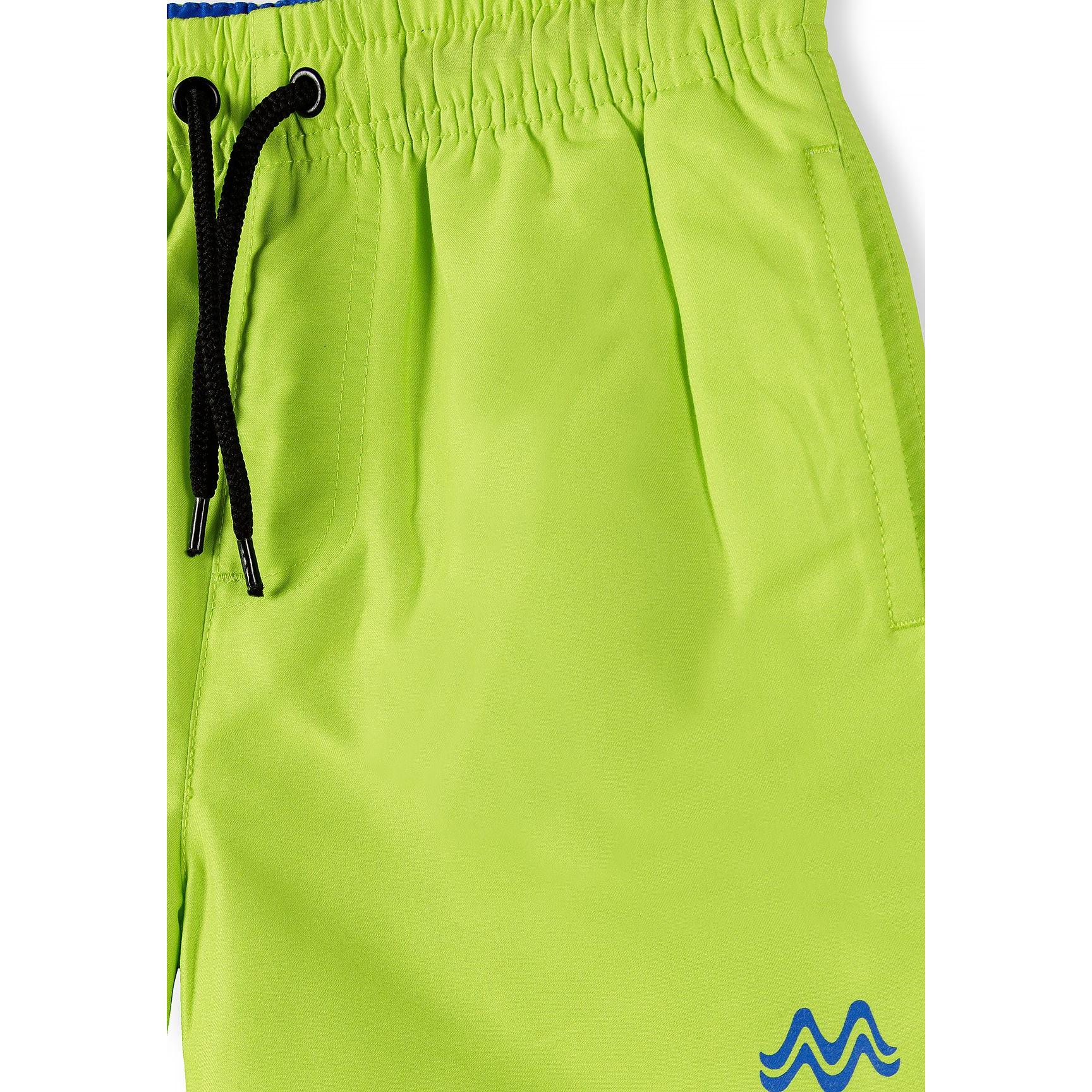 Close-up detail of lime swim shorts showing elastic waistband with blue trim, black drawstring with eyelets and embroidered blue logo