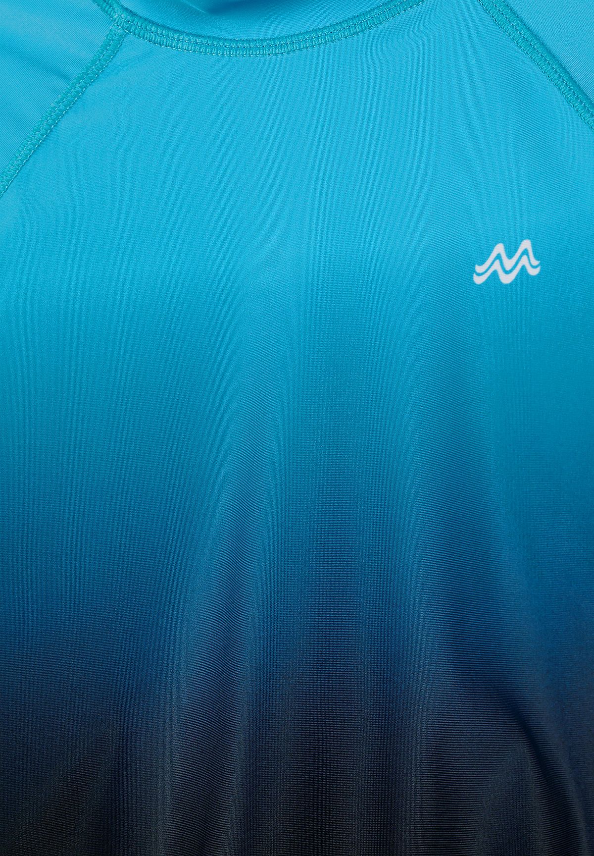 Close-up of gradient rash vest showing turquoise raglan stitching, small white wave logo and blue-to-navy fabric fade.