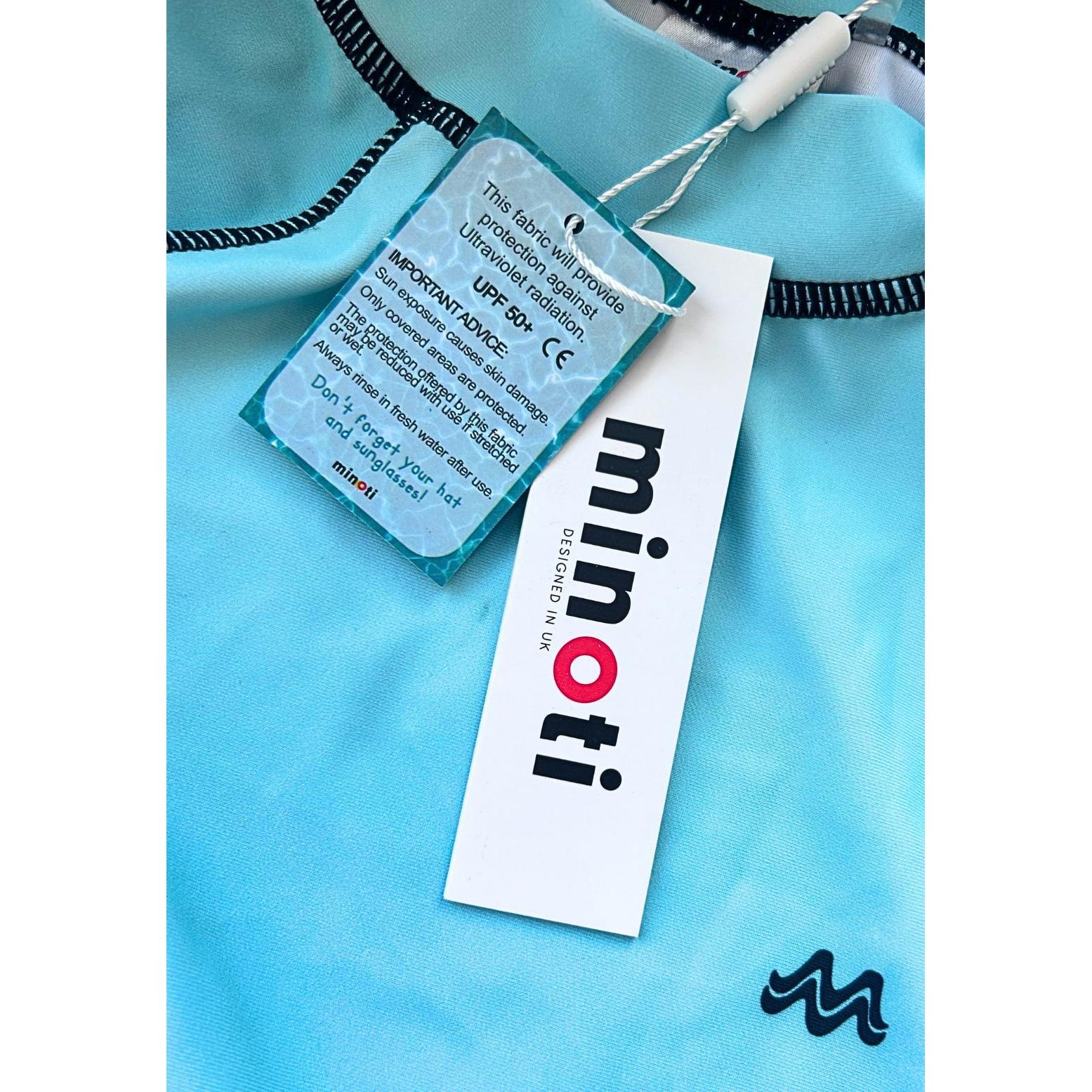 Close-up of light blue swim t-shirt showing Minoti brand tag and UPF 50+ protection label with mountain logo detail