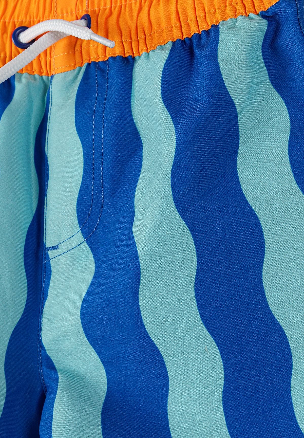 Detail of boys' swimming shorts with blue wavy pattern and elastic waistband.