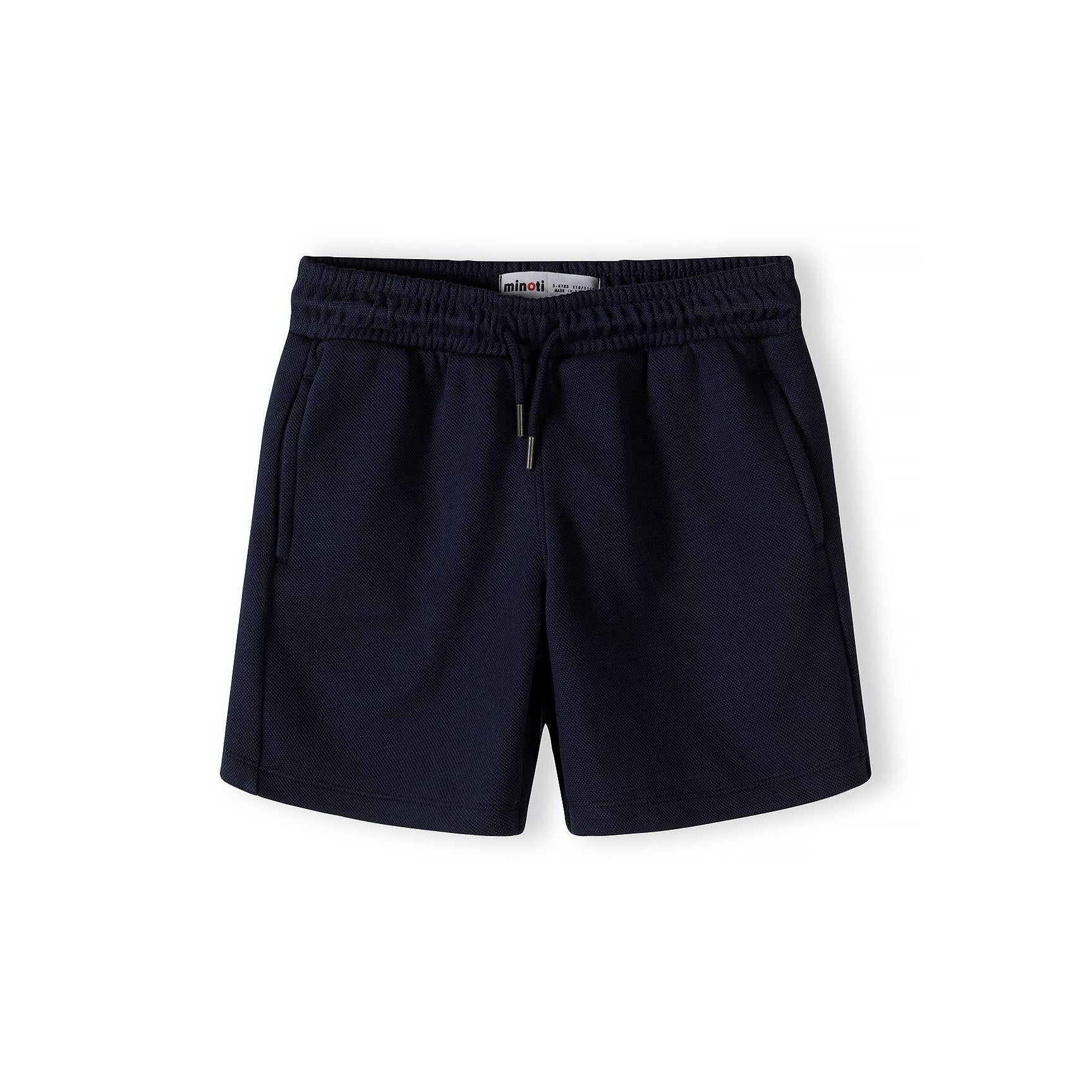 Close-up detail of Minoti label and zip collar on navy and white pique polo shirt showing textured fabric