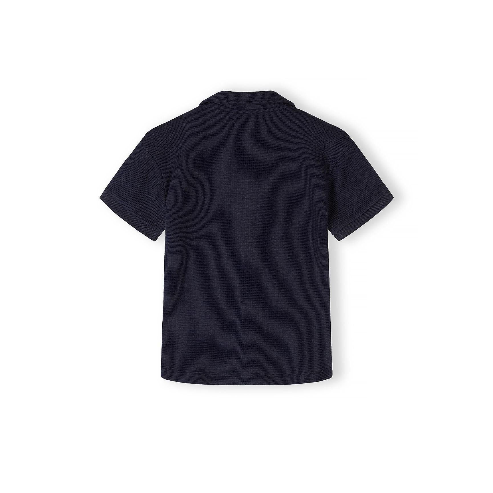 Back view of navy blue short sleeve polo shirt showing textured piqué cotton fabric and structured collar