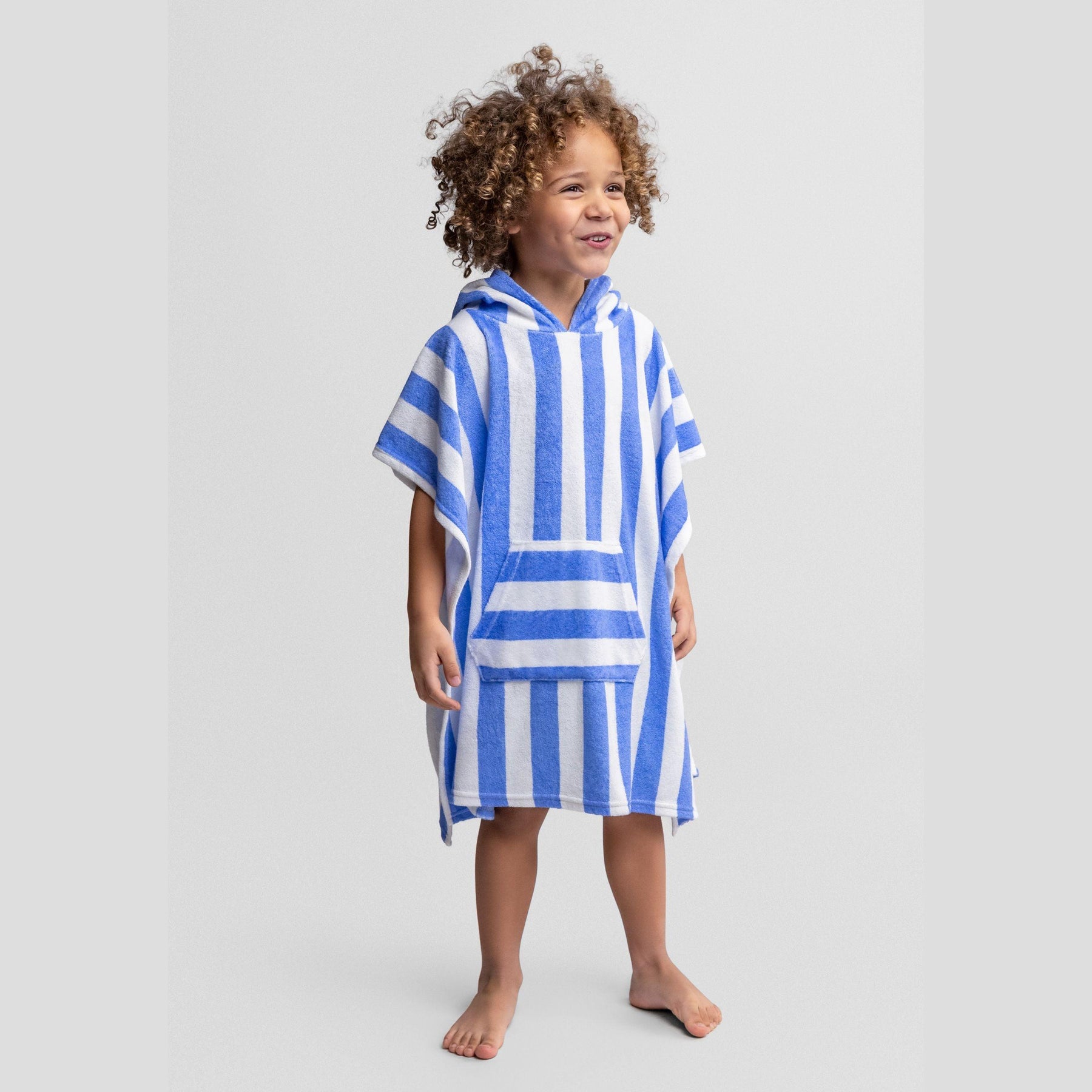 Child wearing blue and white striped hooded towelling cover-up poncho with relaxed fit, standing against white background