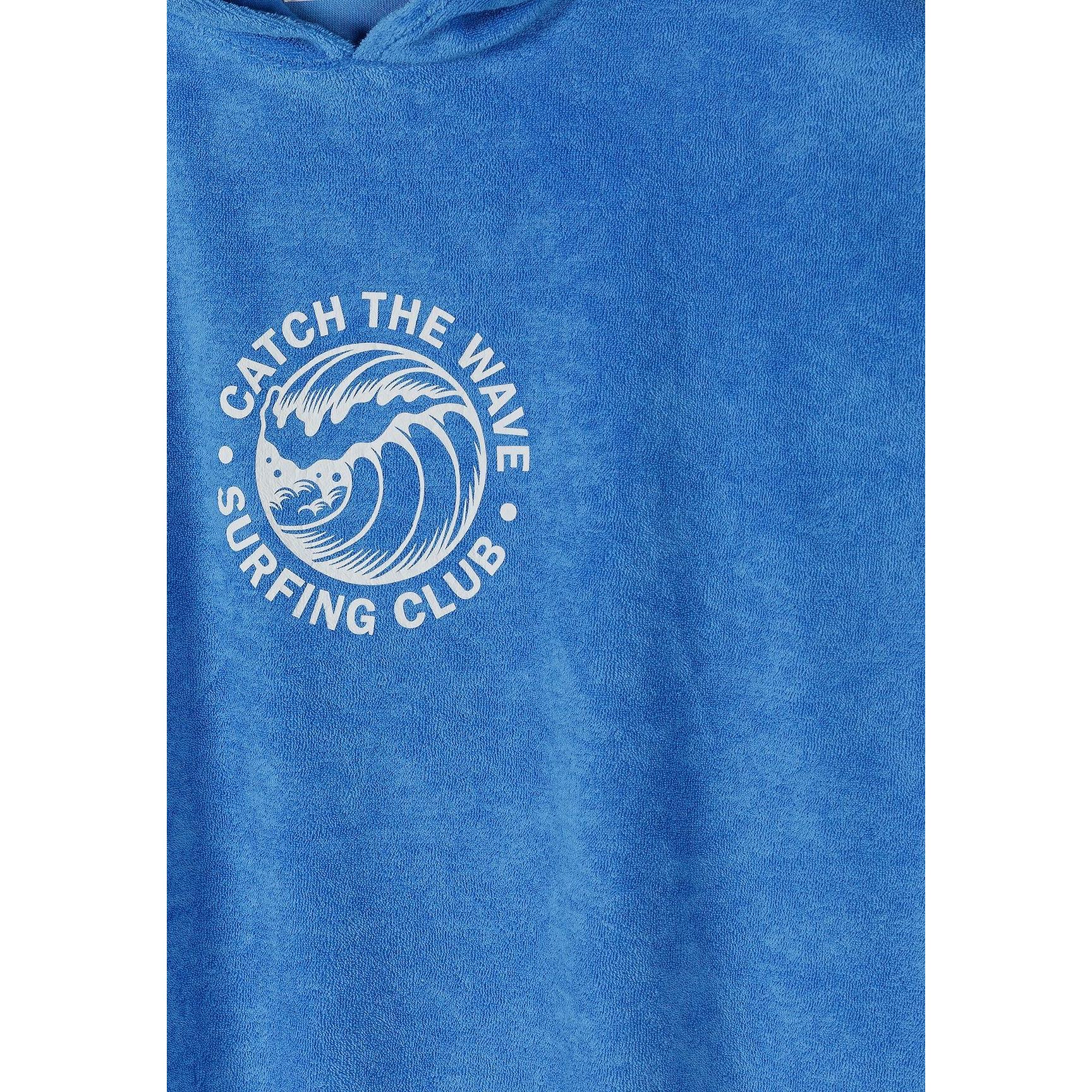 Close-up detail of white Catch the Wave surfing club circular logo with wave design on blue towelling fabric