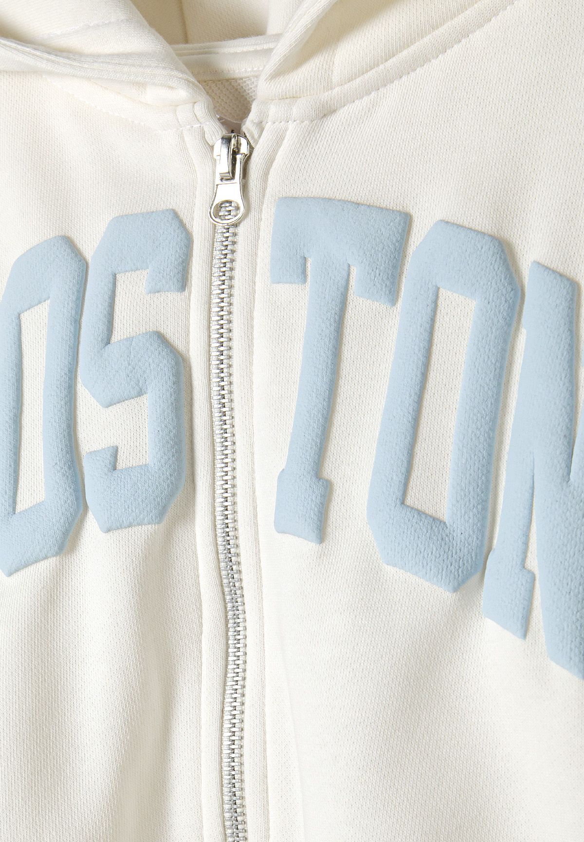 Close-up of cream hoodie zip and raised pale-blue BOSTON chest lettering.