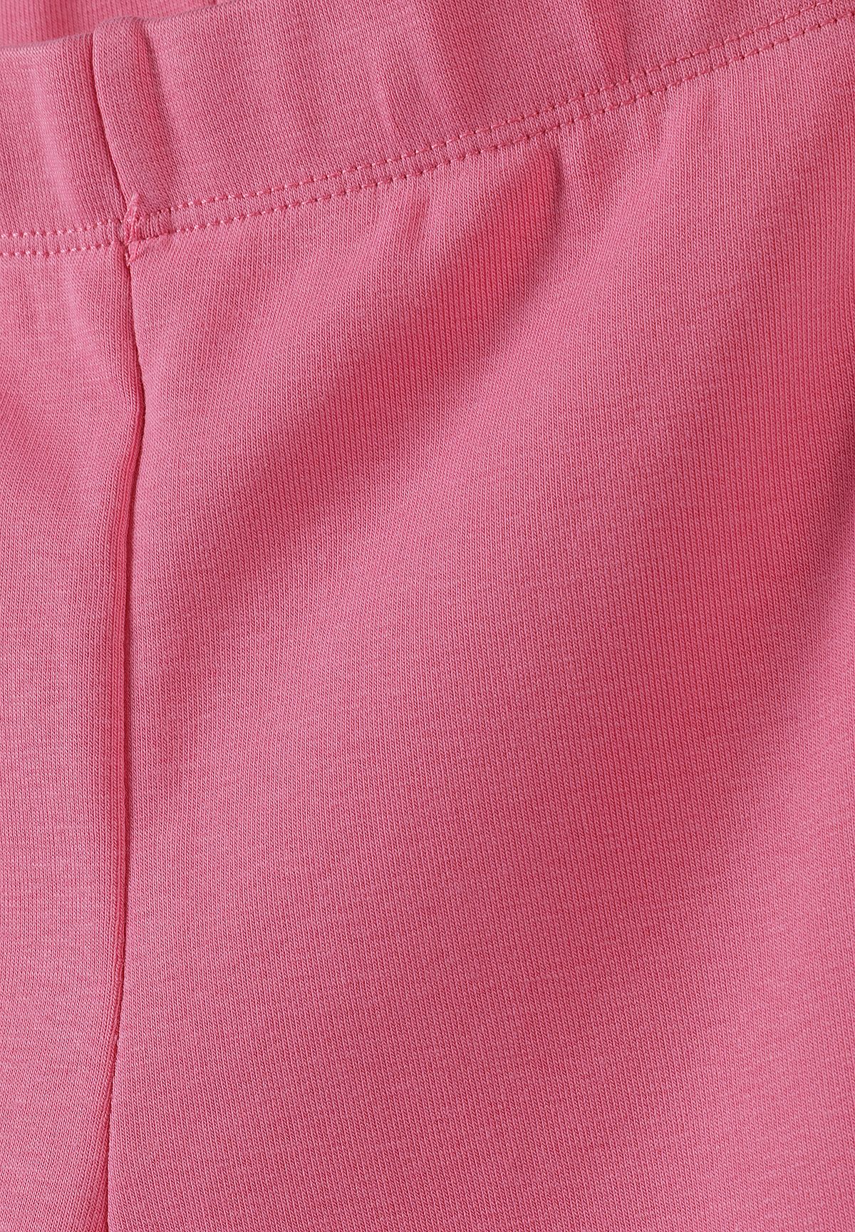 Close-up of pink shorts' elastic waistband, stitched seam and fine ribbed texture.