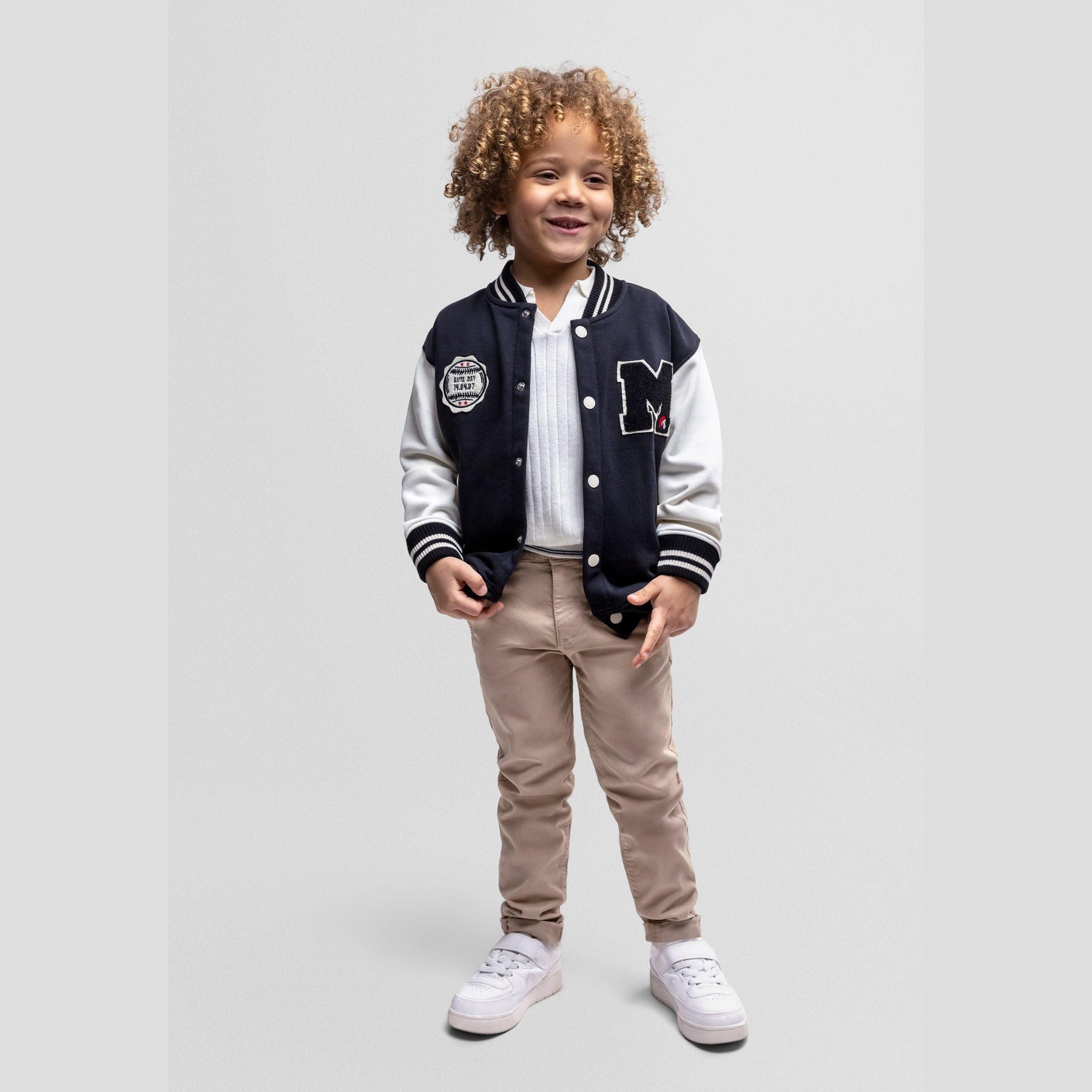 Black baseball jacket with white sleeves laid flat showing front view with M logo patch and button closure