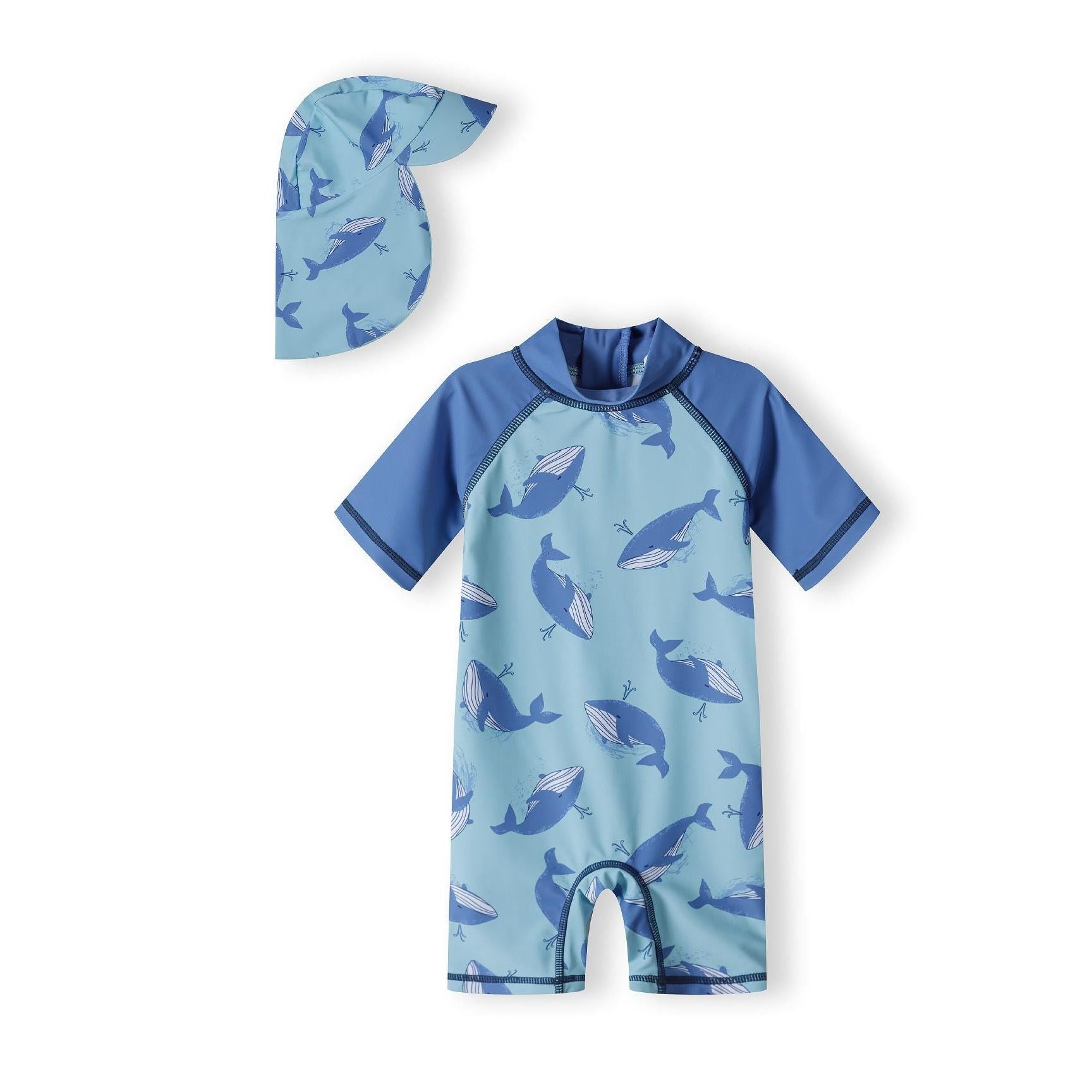 Blue whale print sunsuit with matching hat laid flat on white background, showing short raglan sleeves and all-over marine print