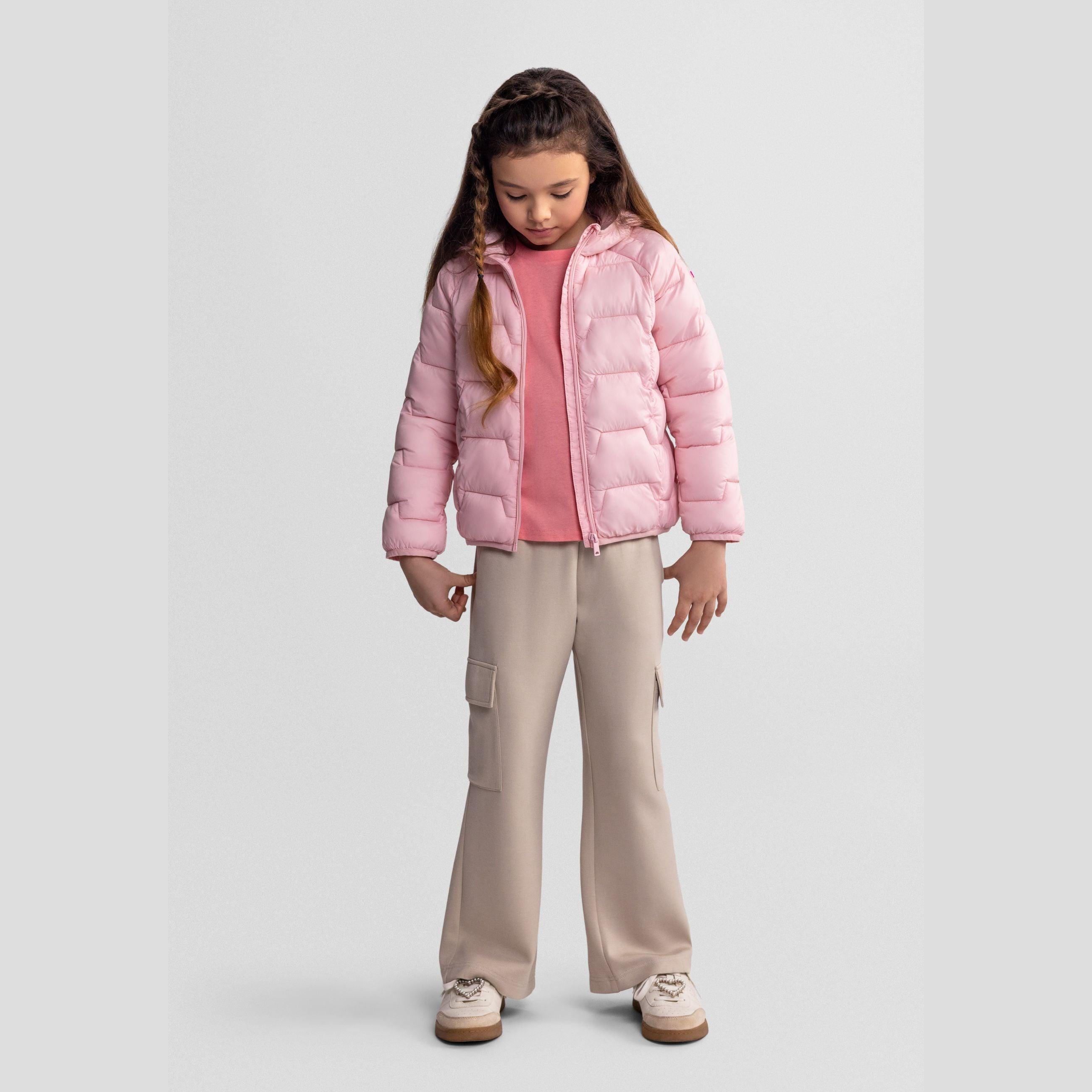 Same girl looking down wearing the pink quilted jacket with hood, showing full outfit styling with beige wide-leg trousers and white trainers