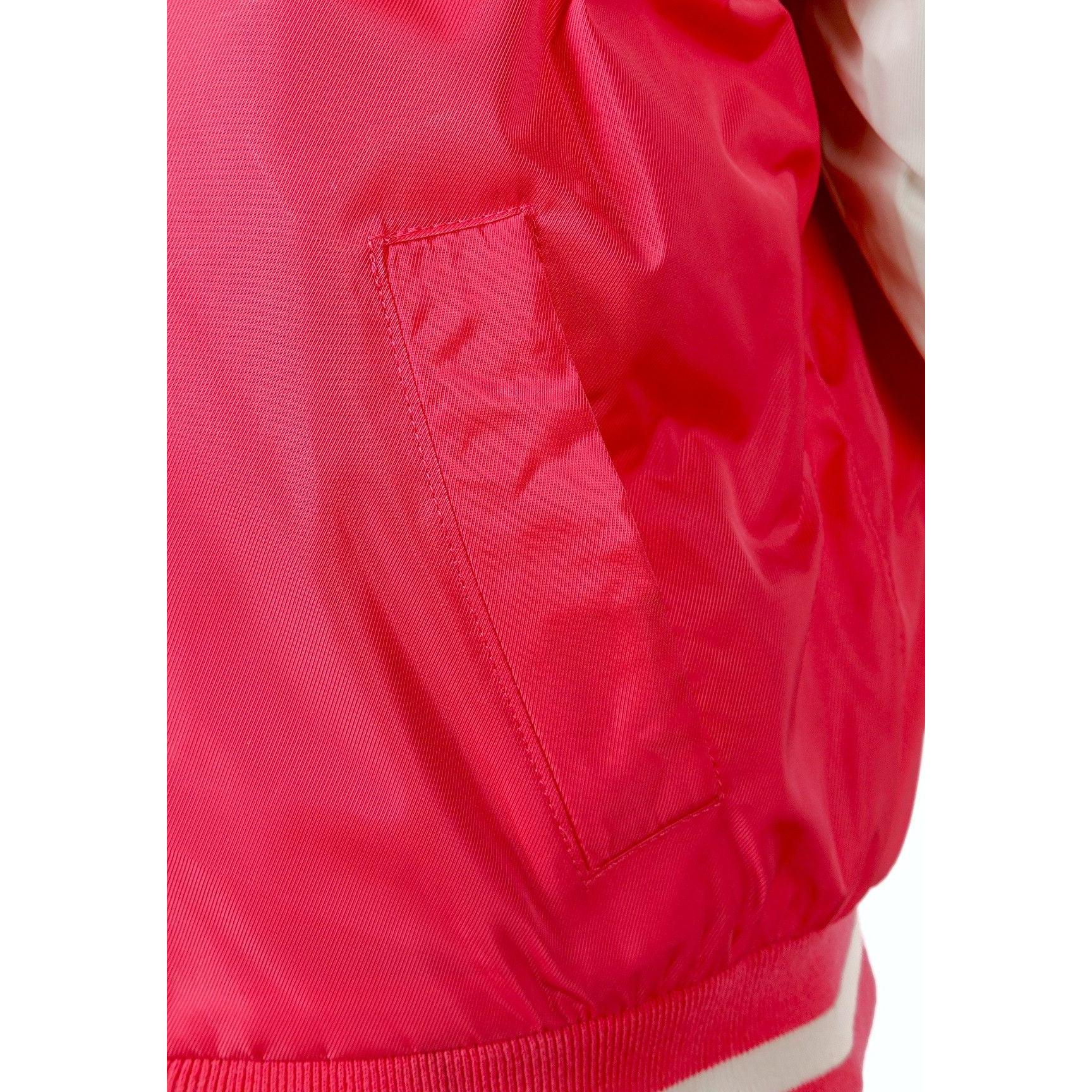 Close-up detail of pink varsity bomber jacket showing side pocket and ribbed trim construction