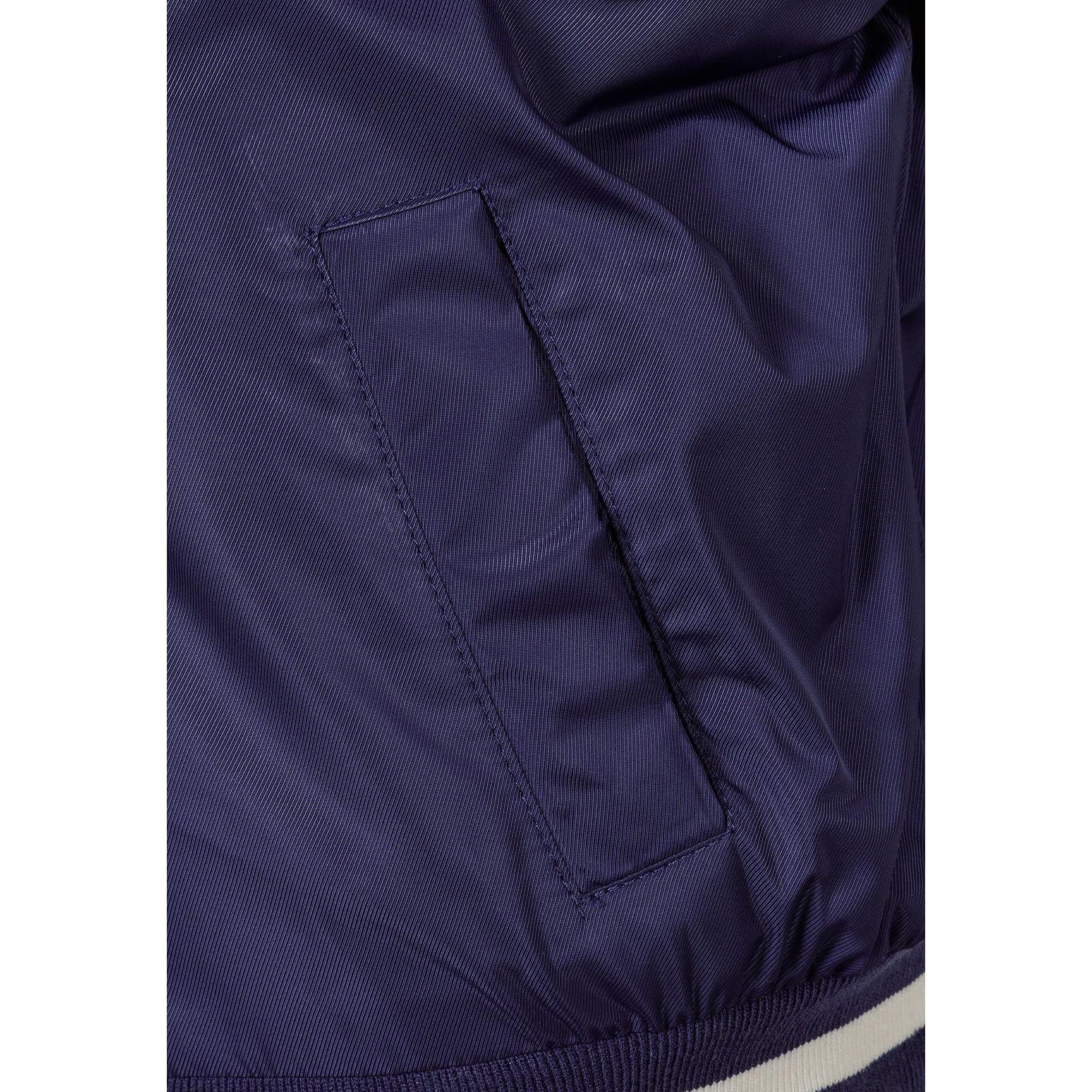 Close-up detail of navy bomber jacket pocket with visible stitching and fabric texture