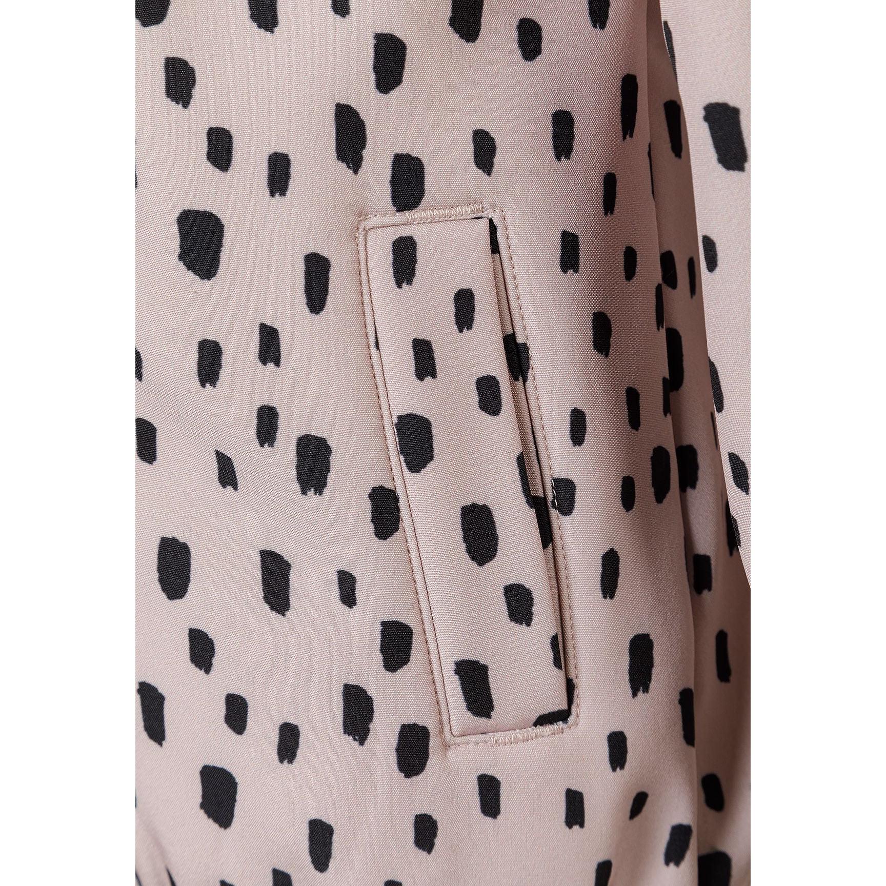Close-up detail of pink fabric with black spotted pattern showing front pocket with stitched edges and fabric texture
