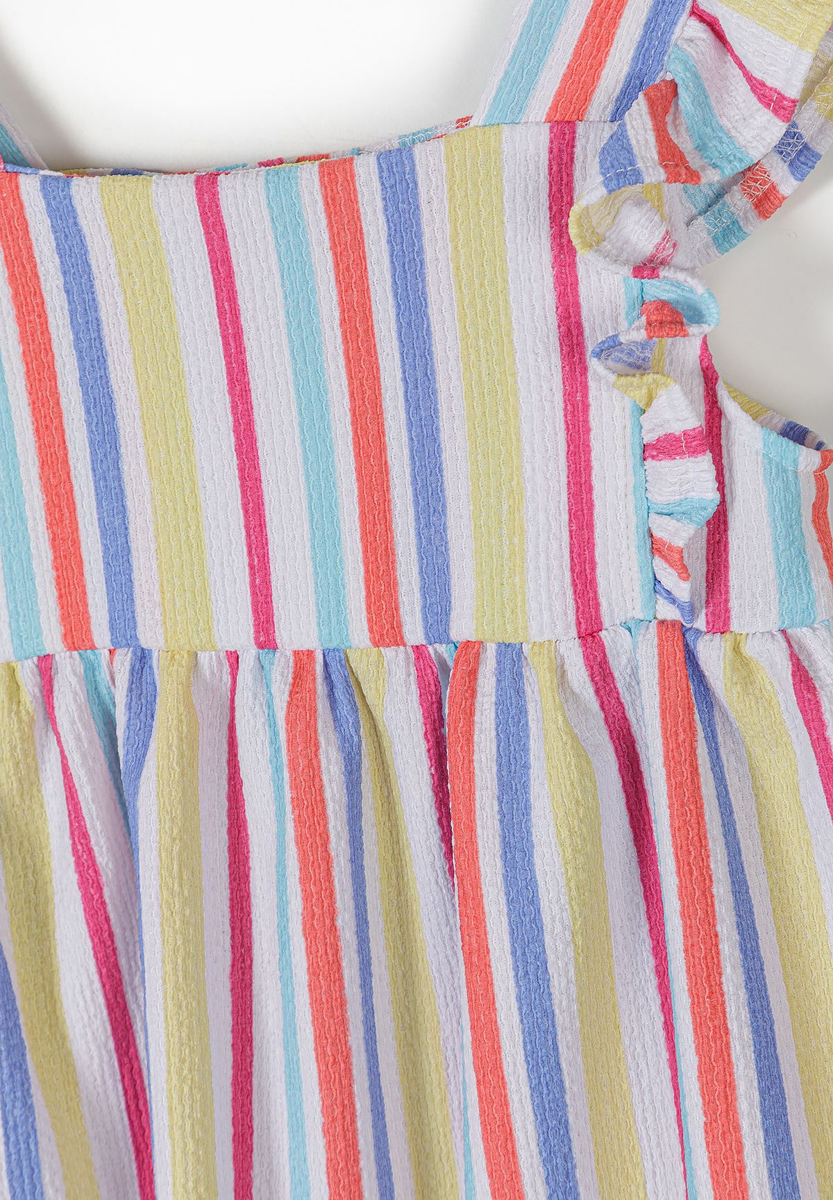 Close-up of girls' sundress showing textured pink, blue, turquoise and yellow stripes, square neckline and shoulder ruffle.