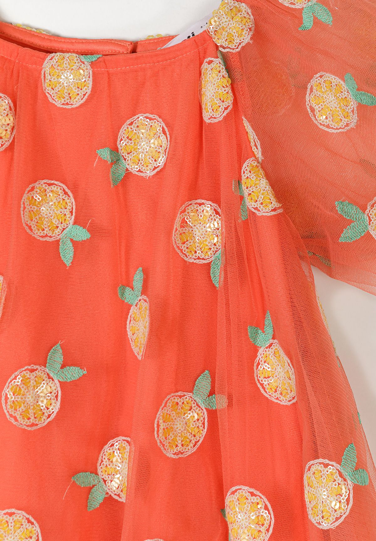 Detail of apricot girls' tulle party dress with sequin embellishments and floral patterns.