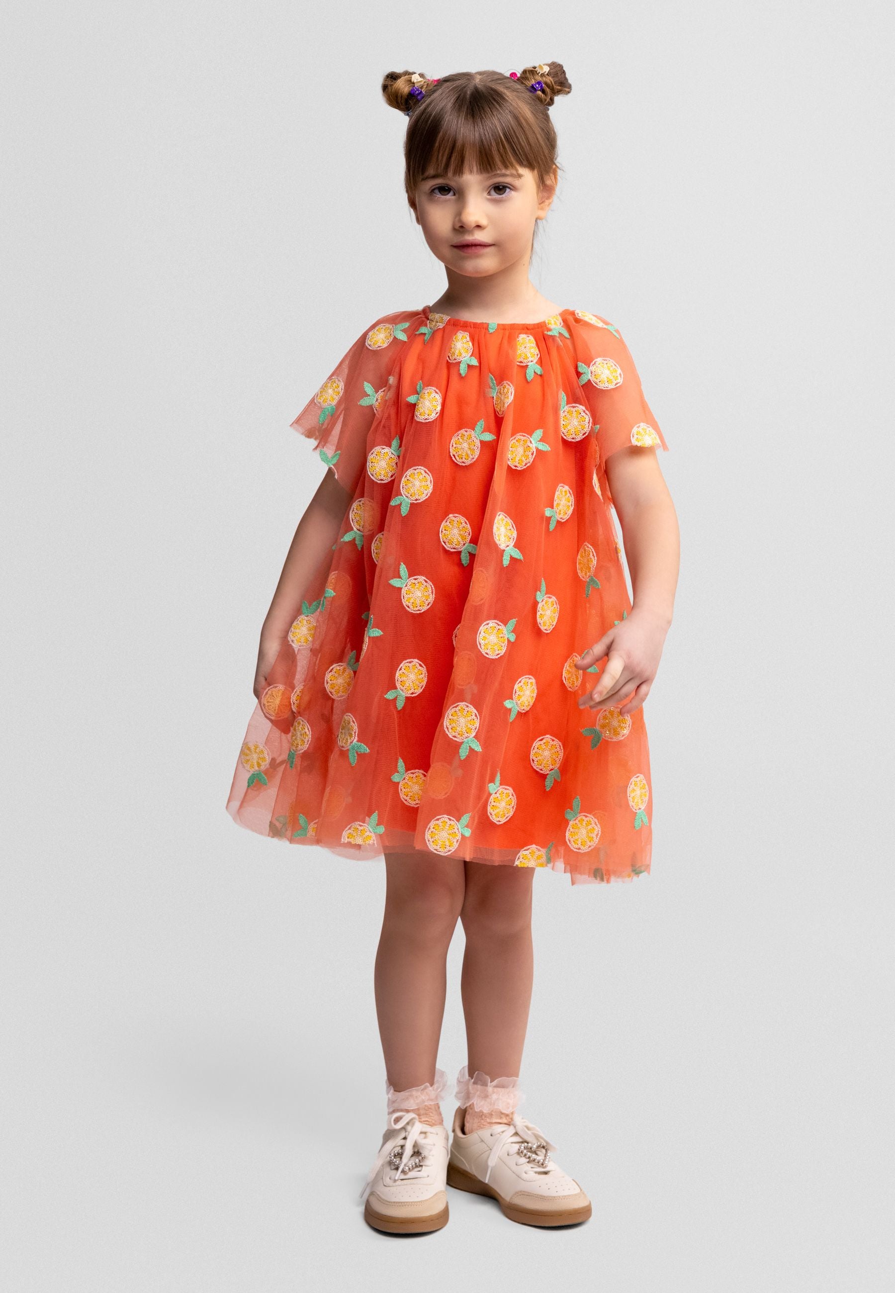 Orange tulle dress laid flat showing angel sleeves, sequin citrus print details, and full silhouette against white background